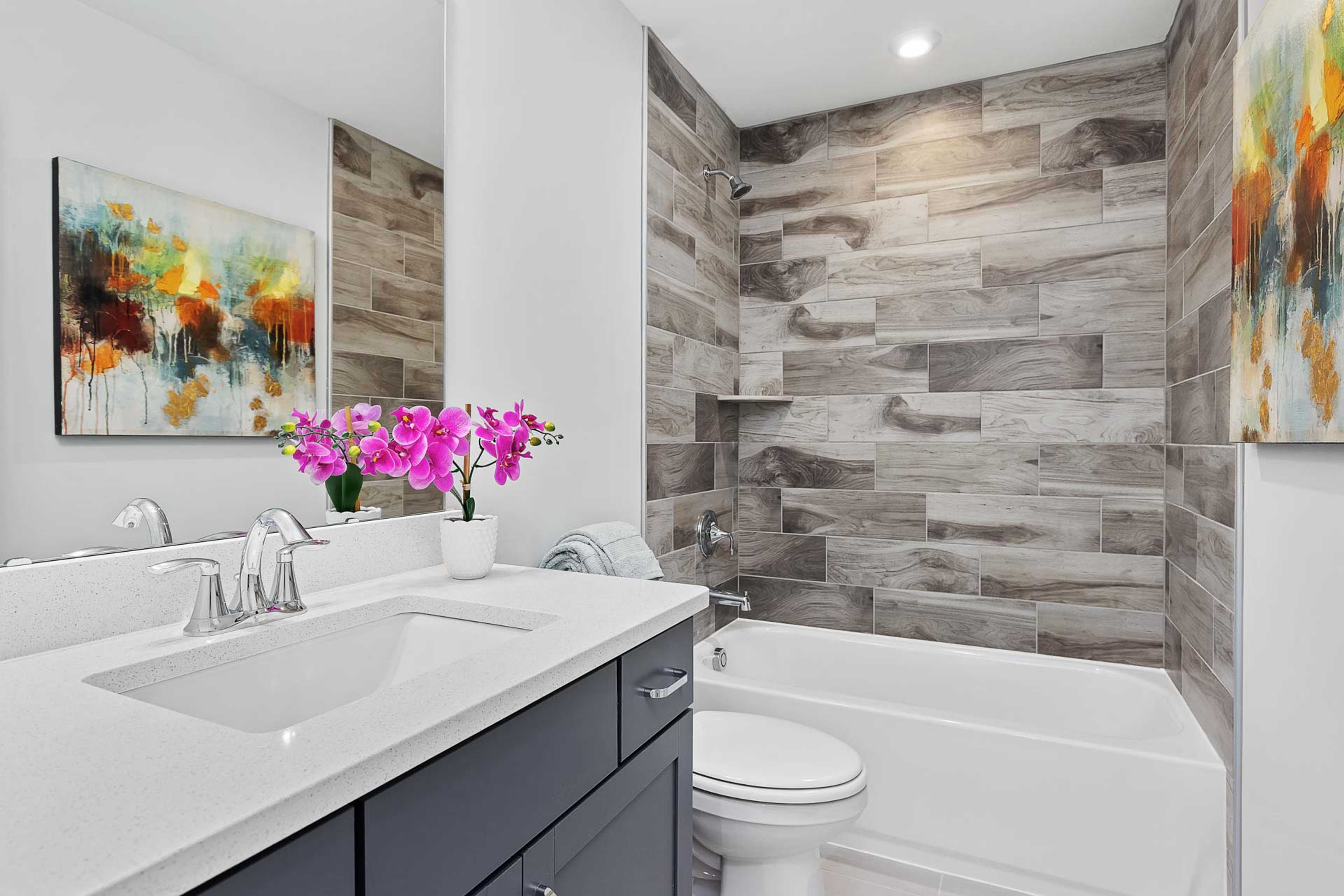 Modern bathroom at Glenmere in Knightdale NC with shiplap walls, freestanding tub, white vanity, and orchids by Davidson Homes