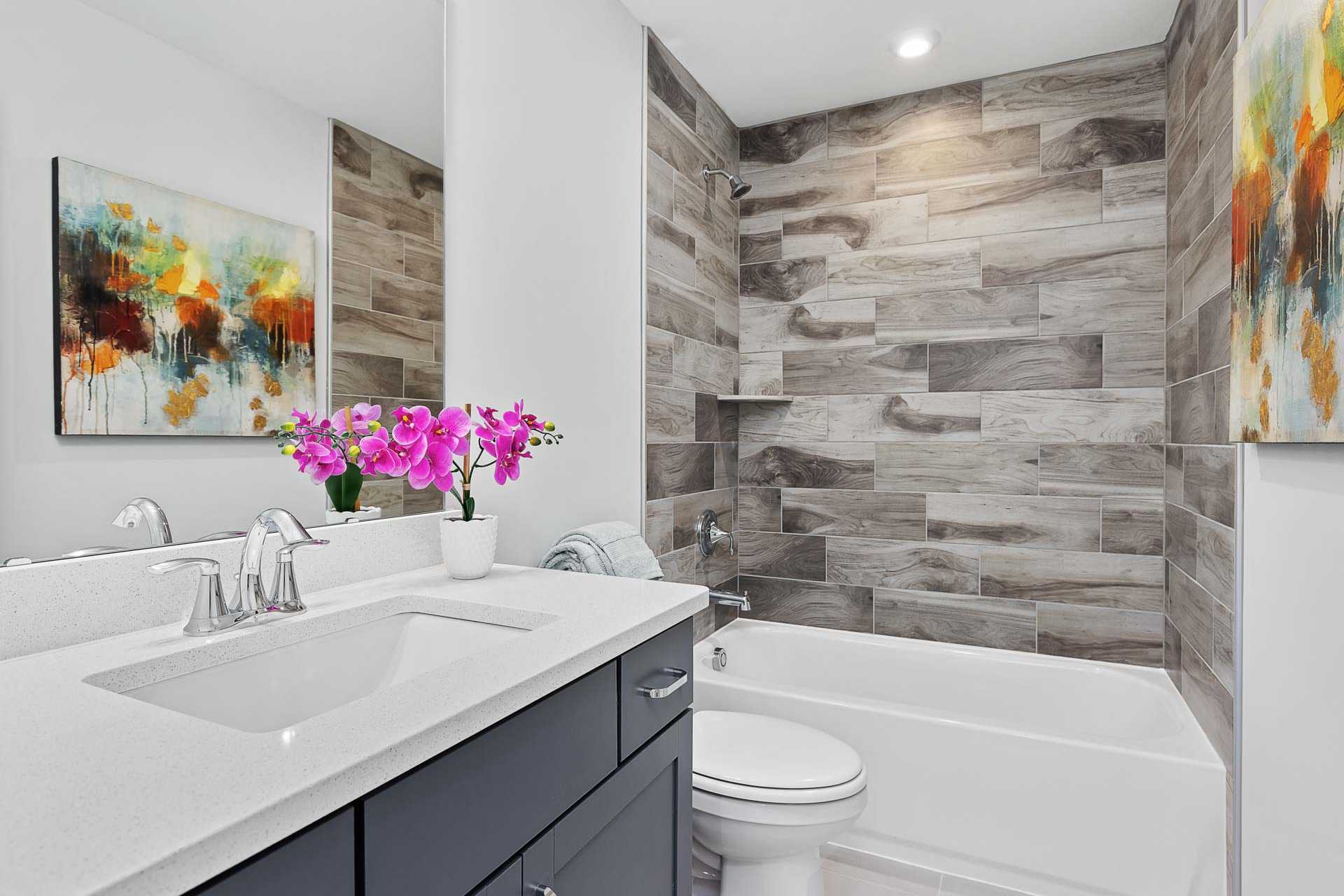 Modern bathroom at Glenmere in Knightdale NC with shiplap walls, freestanding tub, white vanity, and orchids by Davidson Homes