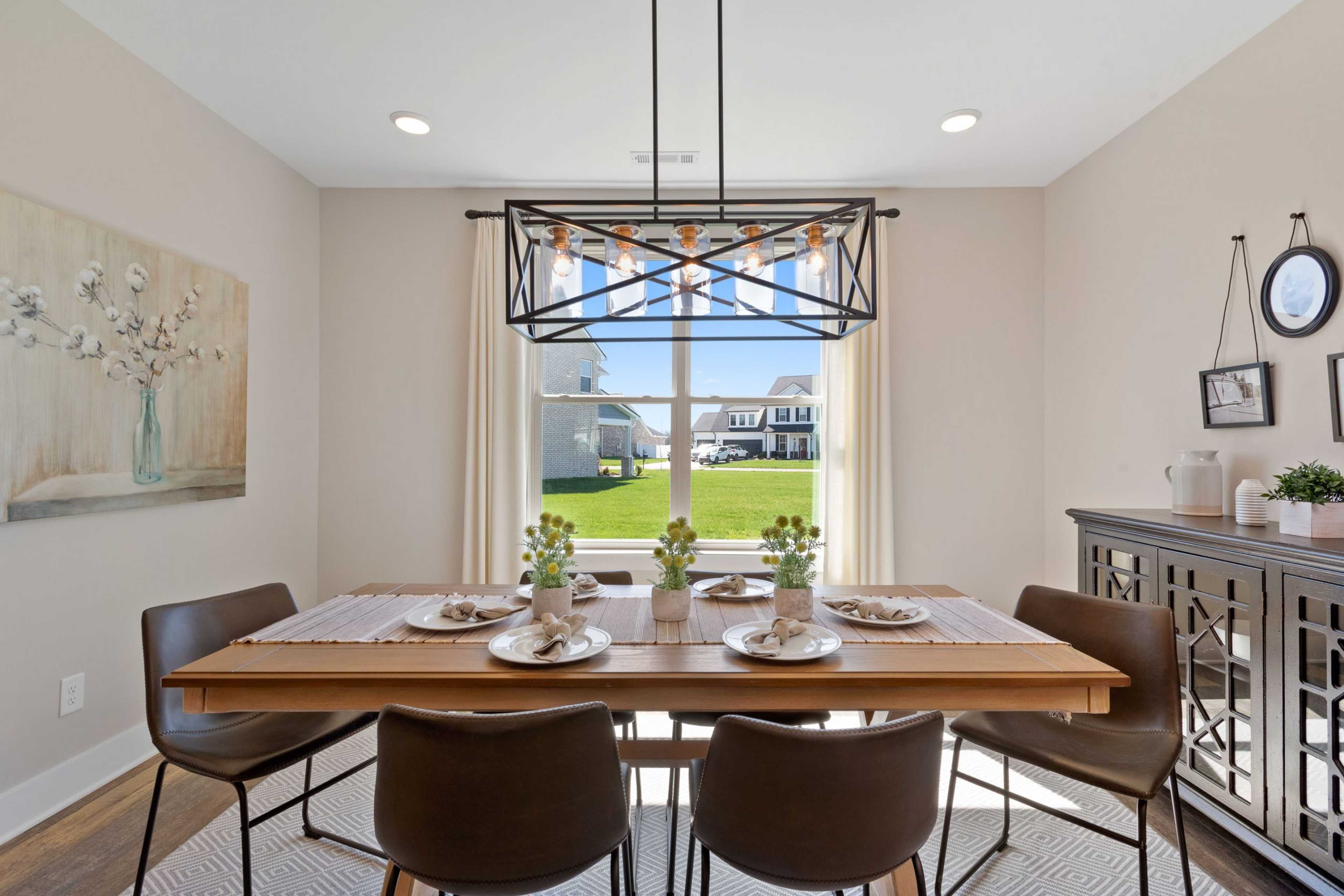 Spacious dining room at Rivers Edge in Murfreesboro TN featuring wooden table with place settings, pendant light, and window view of green lawn