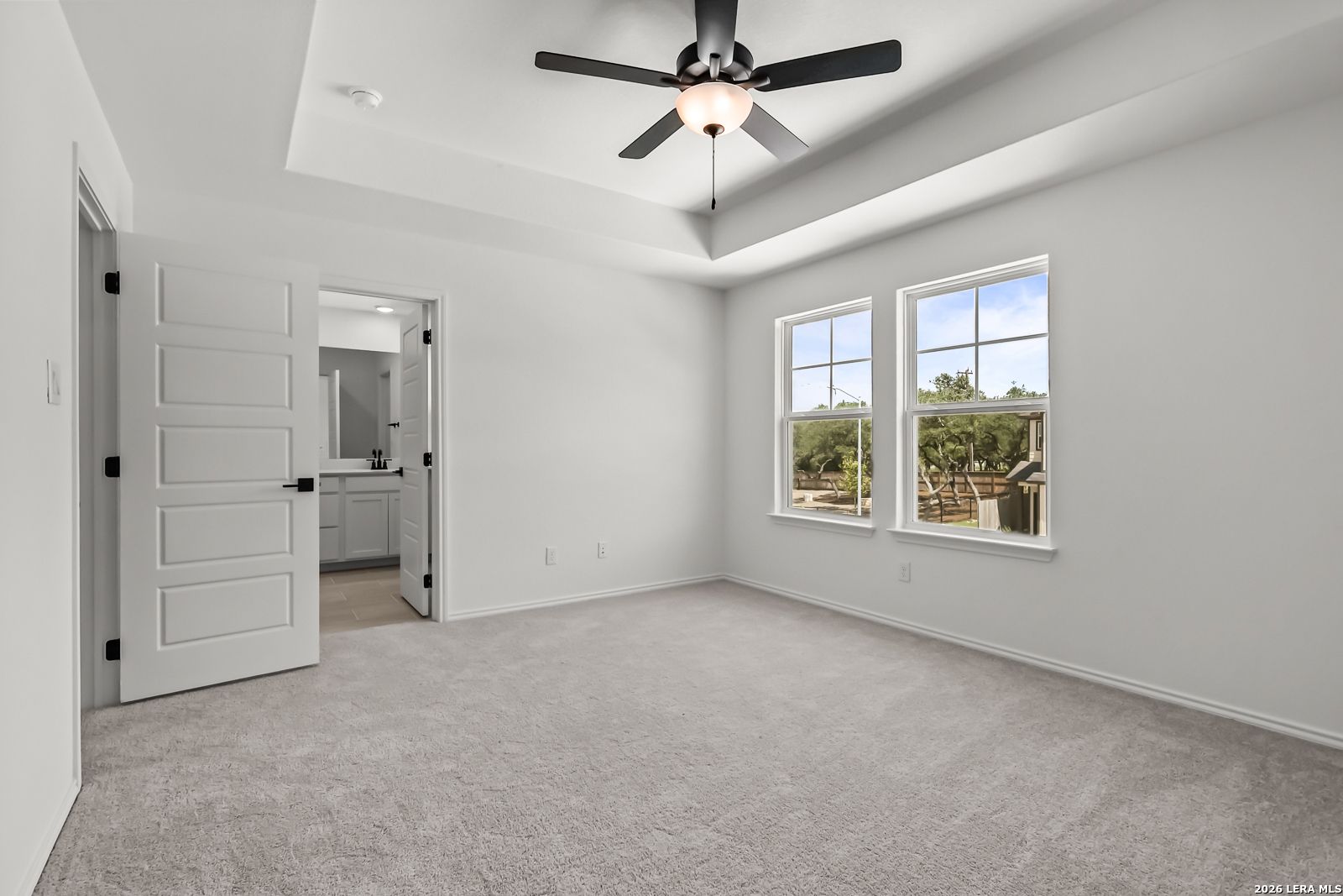 Primary bedroom with tray ceiling and en-suite bath in The Florence B floor plan at Meadows at Oak Creek, San Antonio.
