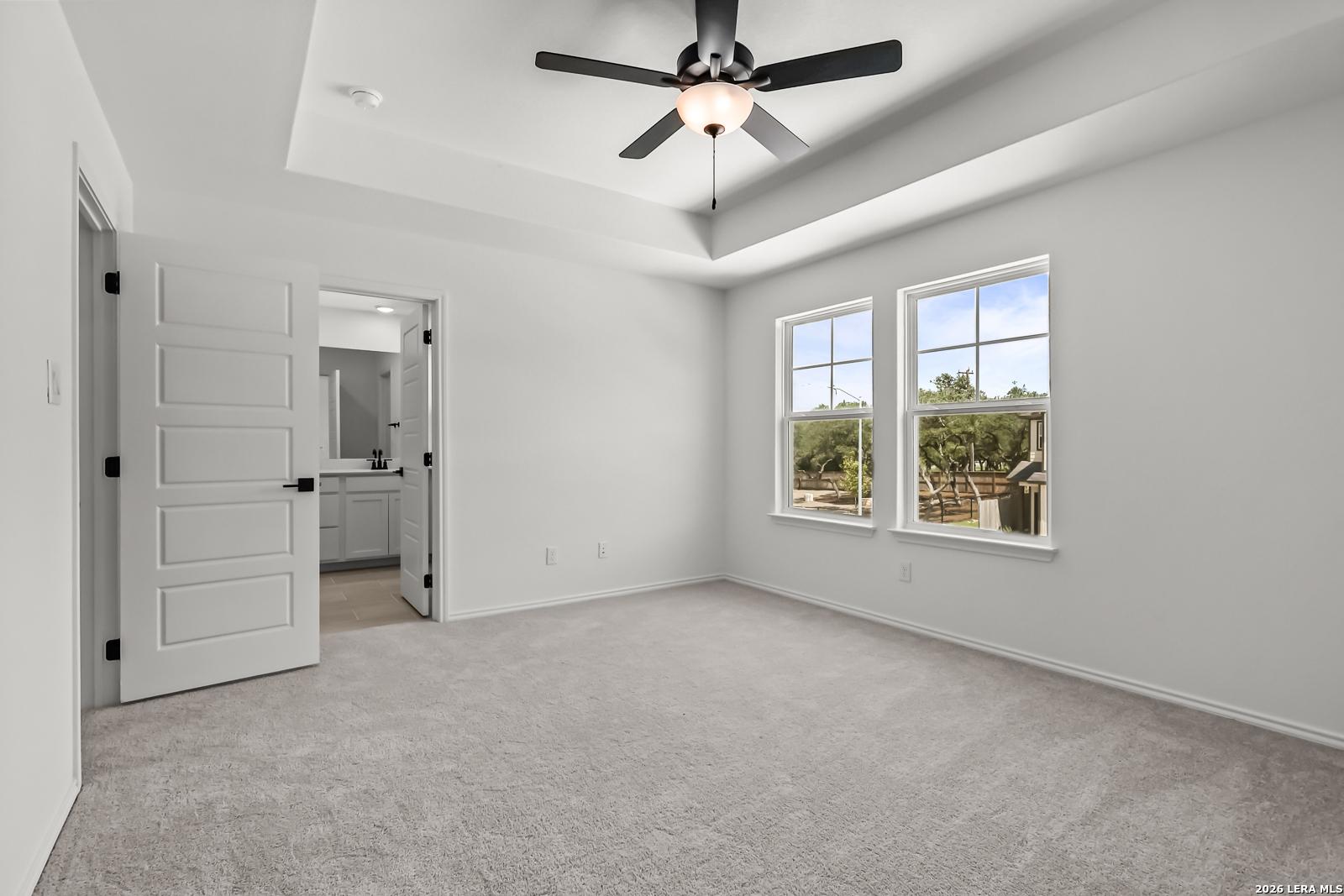 Primary bedroom with tray ceiling and en-suite bath in The Florence B floor plan at Meadows at Oak Creek, San Antonio.