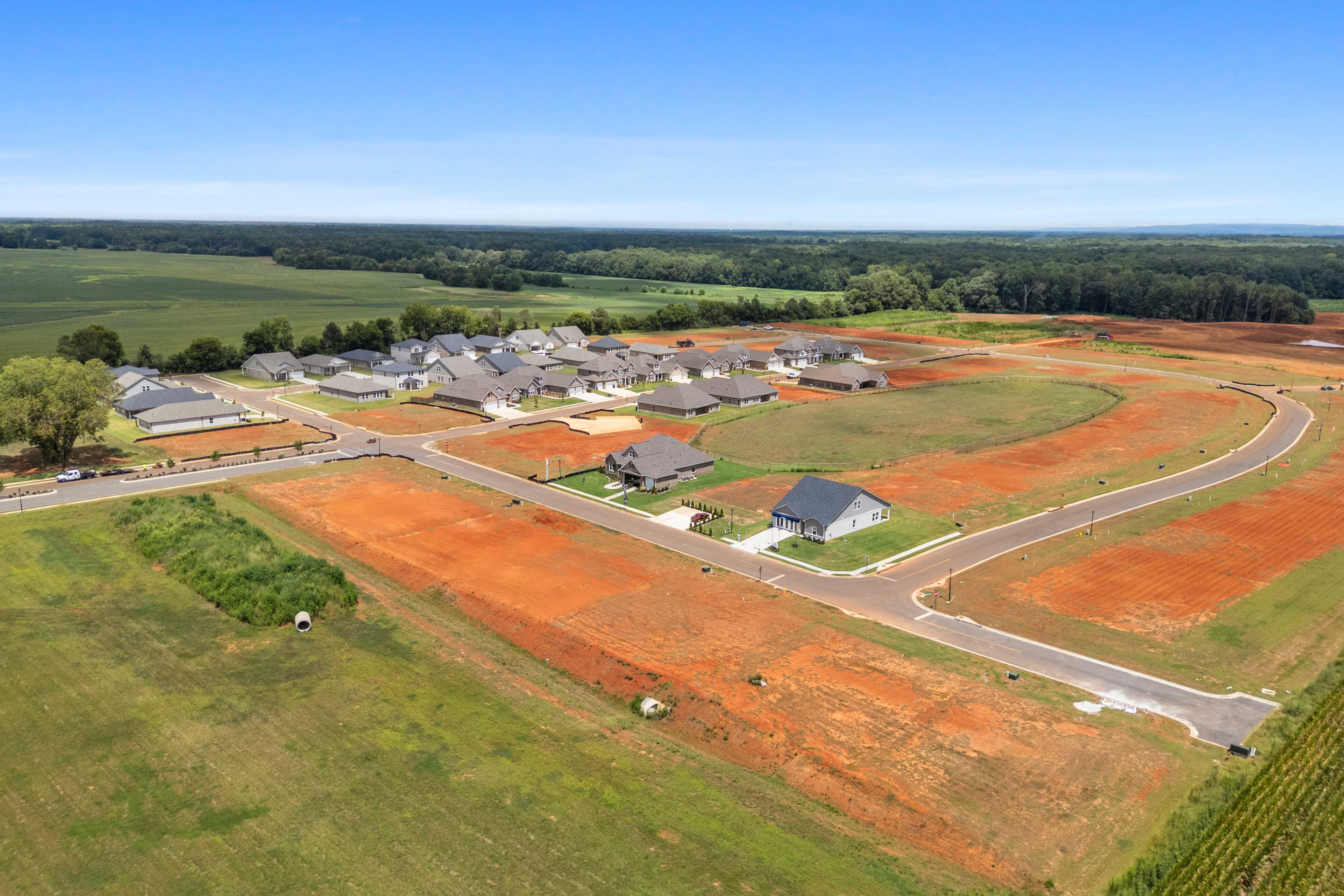 Aerial view of new homes at Kendall Farms in Toney, Alabama with curved streets, red clay lots, and surrounding green fields