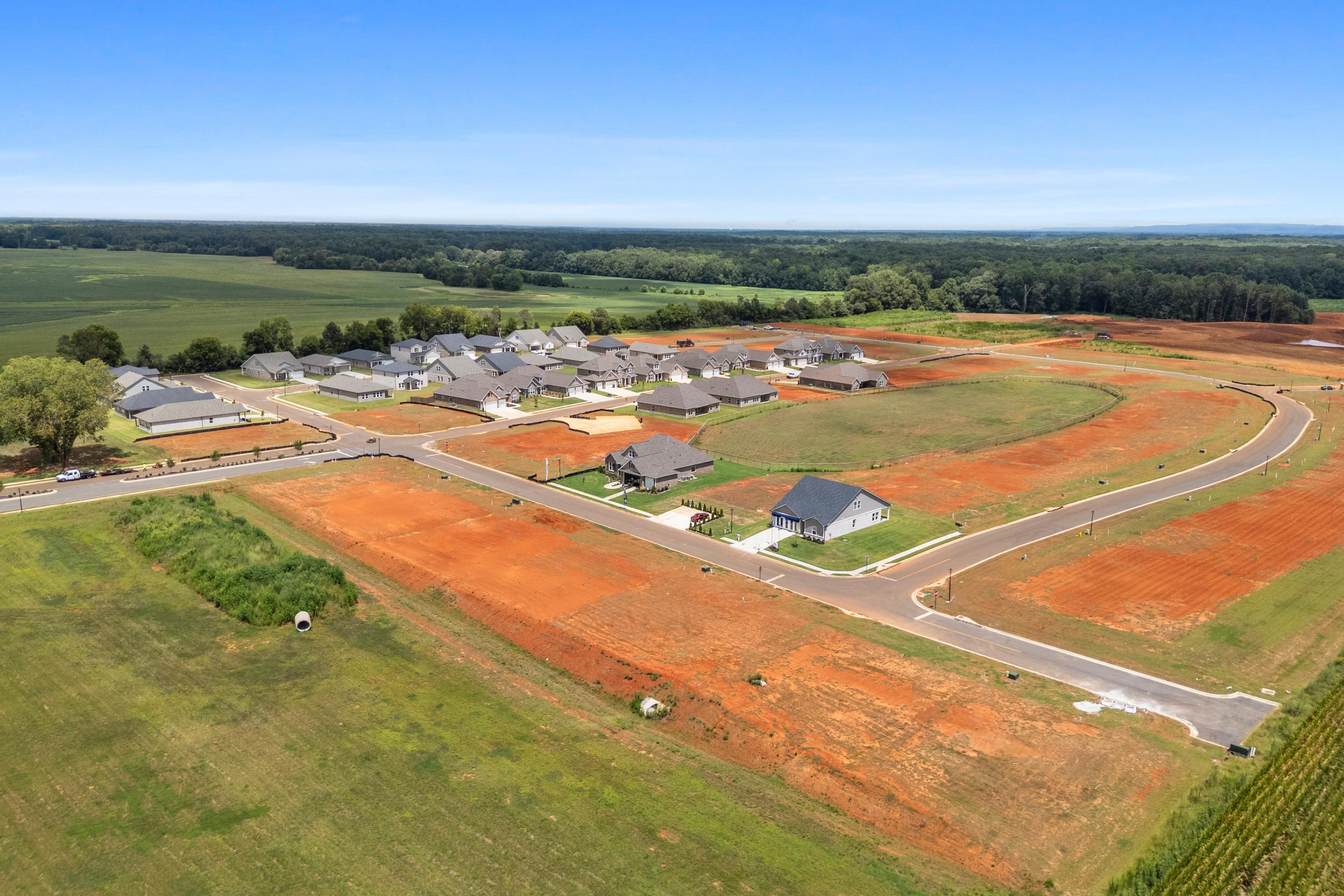 Aerial view of new homes at Kendall Farms in Toney, Alabama with curved streets, red clay lots, and surrounding green fields