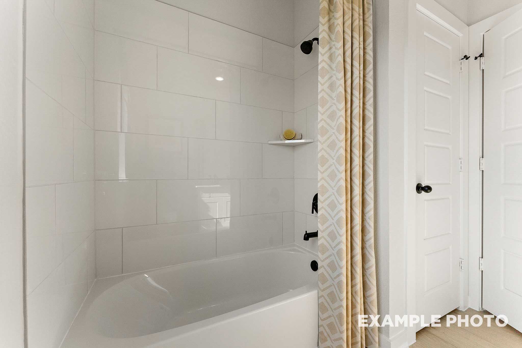 Modern bathroom with white subway tile shower-tub combo in The Everett E floor plan by Davidson Homes in Crosby, Texas.
