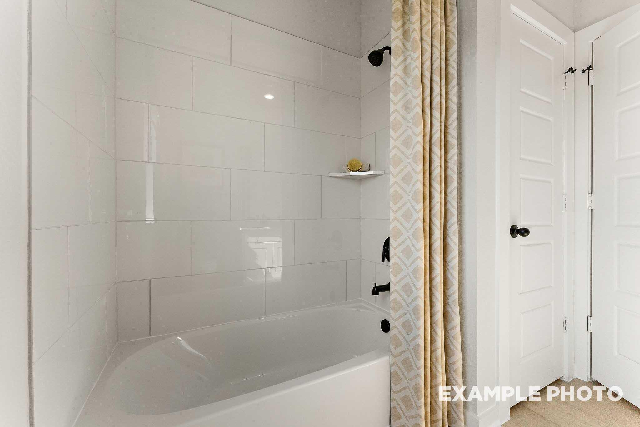 Modern bathroom with white subway tile shower-tub combo in The Everett E floor plan by Davidson Homes in Crosby, Texas.