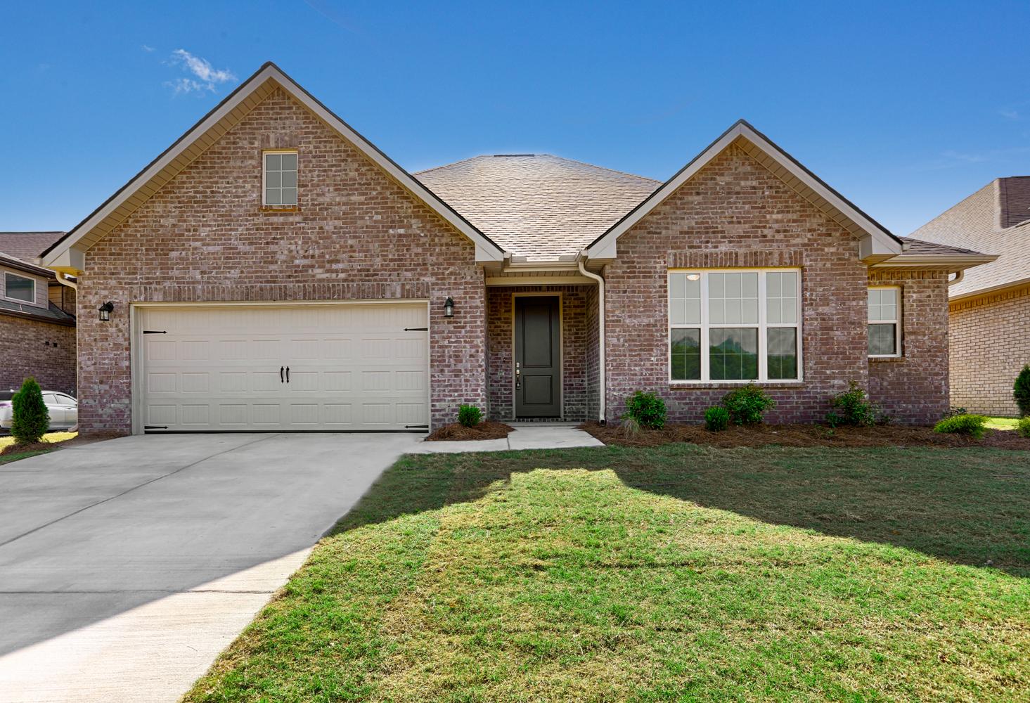Modern brick facade of The Montgomery 1-story home featuring gabled roof, 2-car garage, and landscaped yard in Meridianville, AL