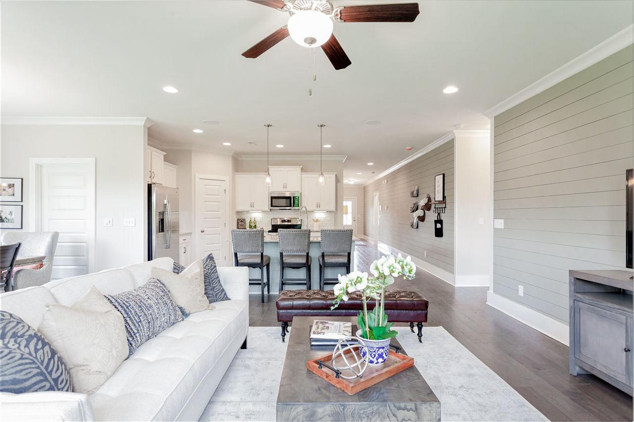 Open-concept living room and kitchen in Williams Pointe Huntsville AL with white sofa, hardwood floors, and bar island