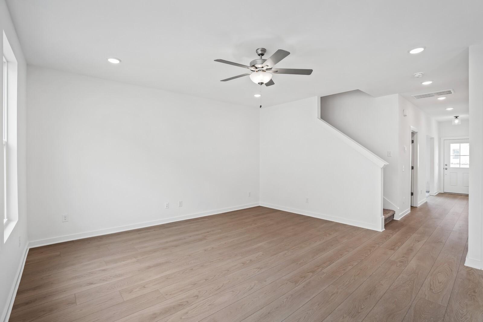 Spacious entry foyer with hardwood floors, white walls, ceiling fan, and staircase in Davidson Homes The Logan C, Calista Farms