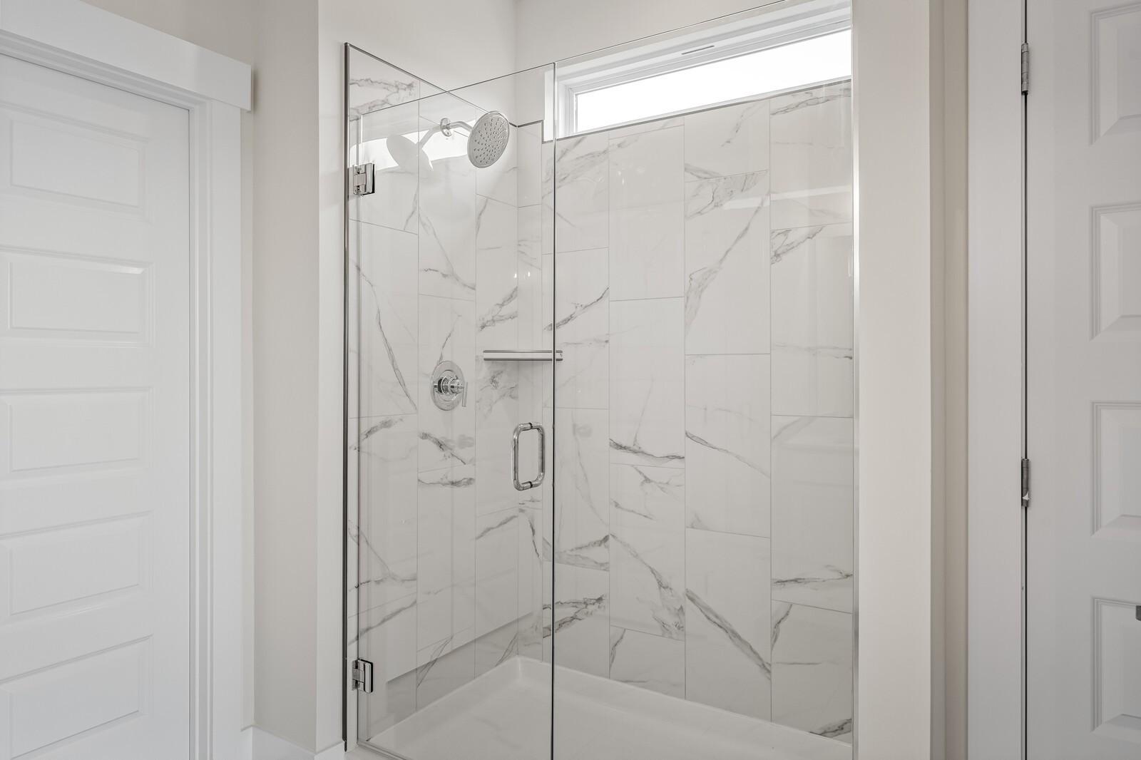Walk-in shower with marble-look tile and glass door in The Ridgeport D floor plan by Davidson Homes in Mt. Juliet, TN.