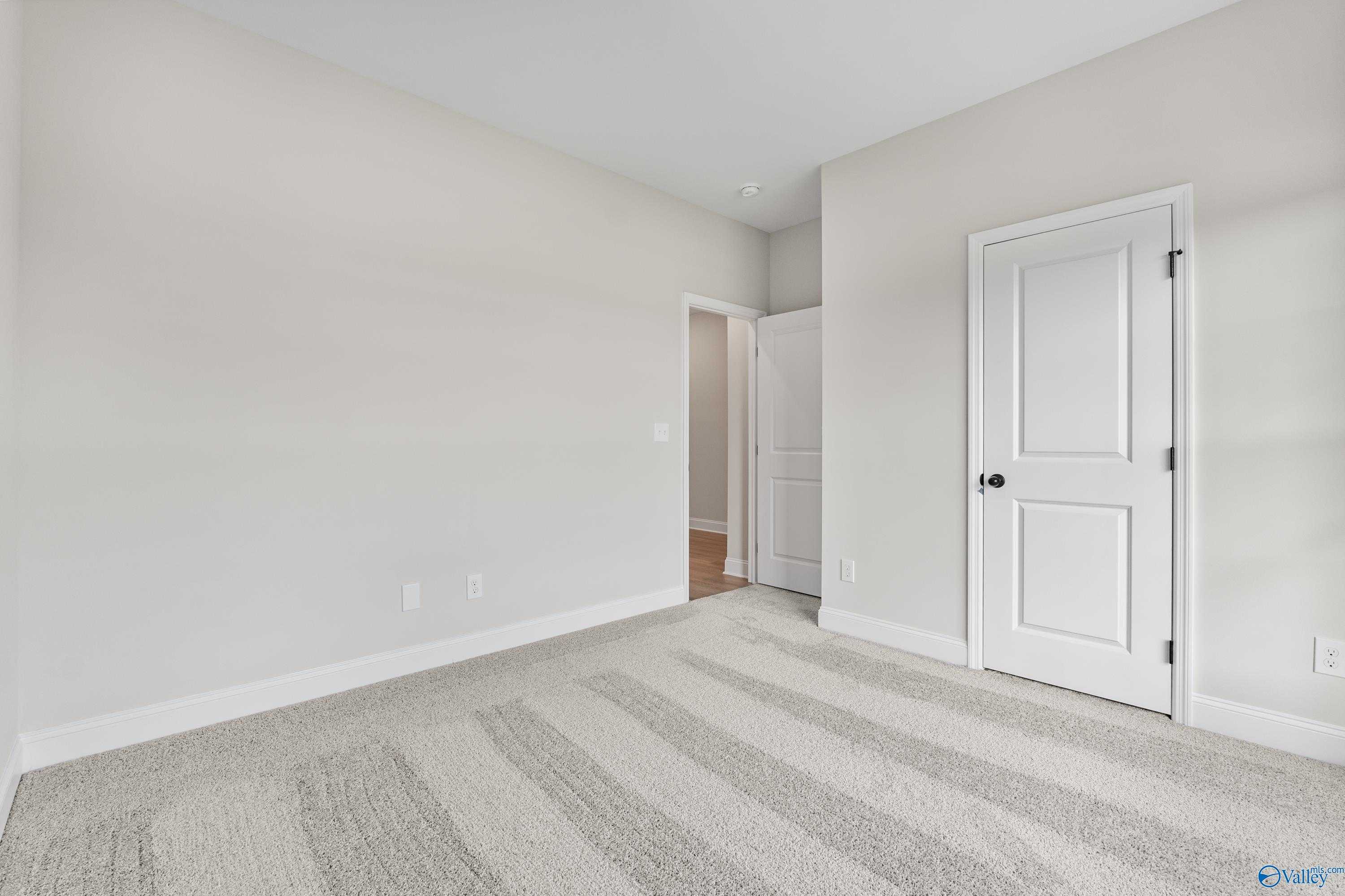 Spacious secondary bedroom with neutral walls, plush carpet, and interior doors in Davidson Homes The Franklin B, Hazel Green, AL