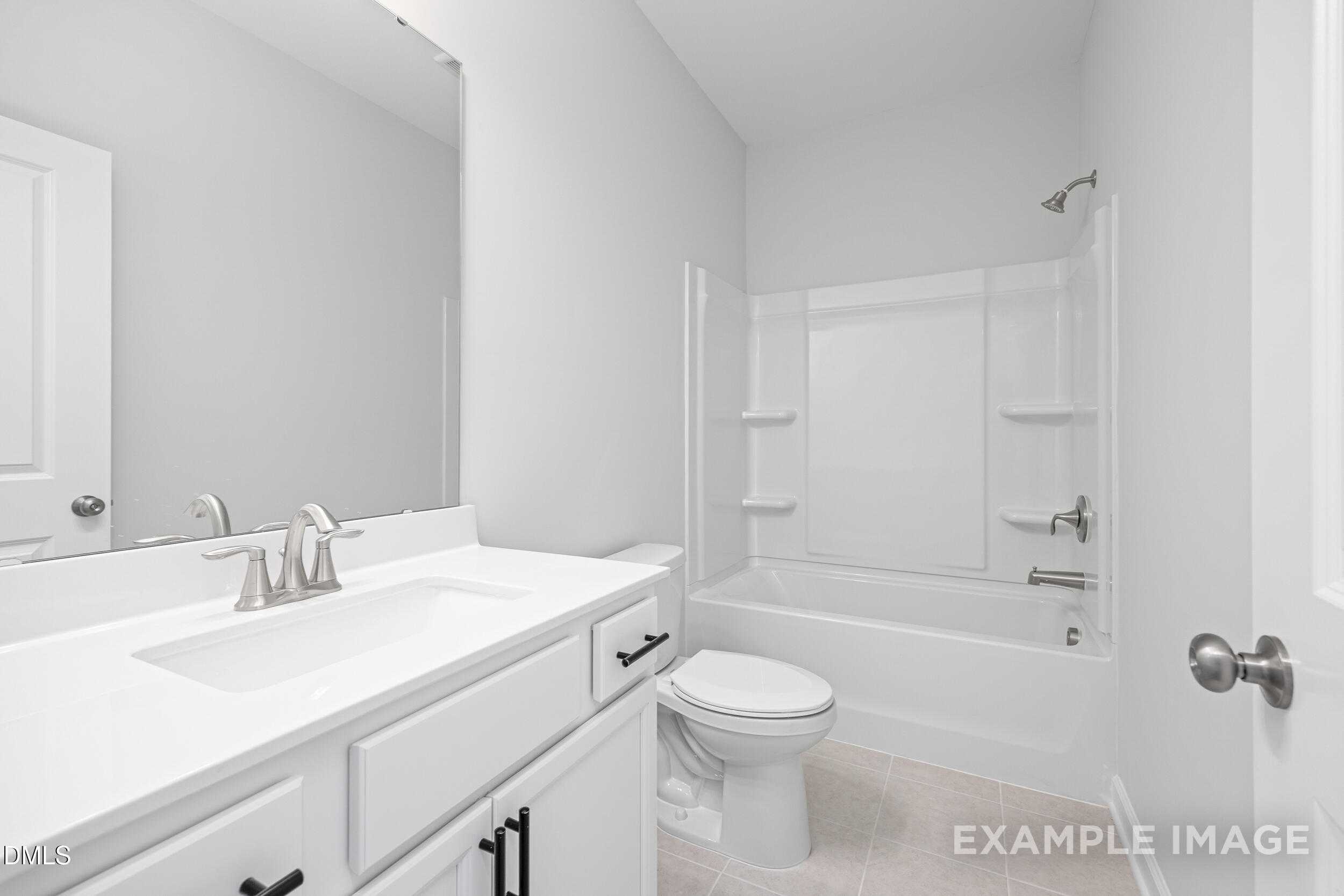 Modern white bathroom with vanity sink, tub-shower combo, and toilet in Davidson Homes The Franklin C, Lillington, NC