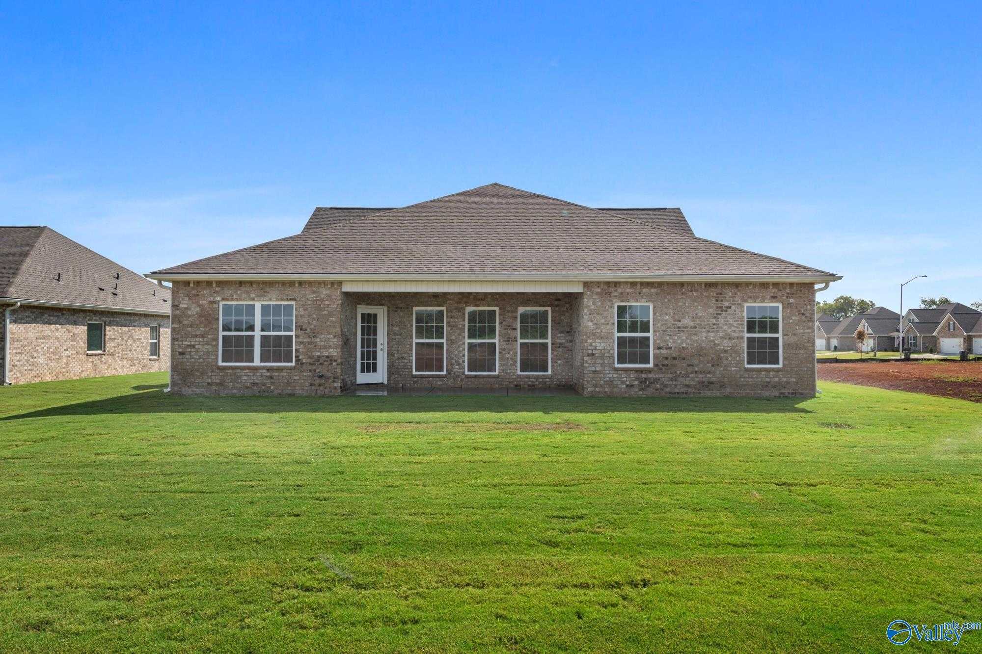 Brick single-story home with covered back patio, French doors, and large windows on lush green lawn in Pikes Ridge, Meridianville, Alabama