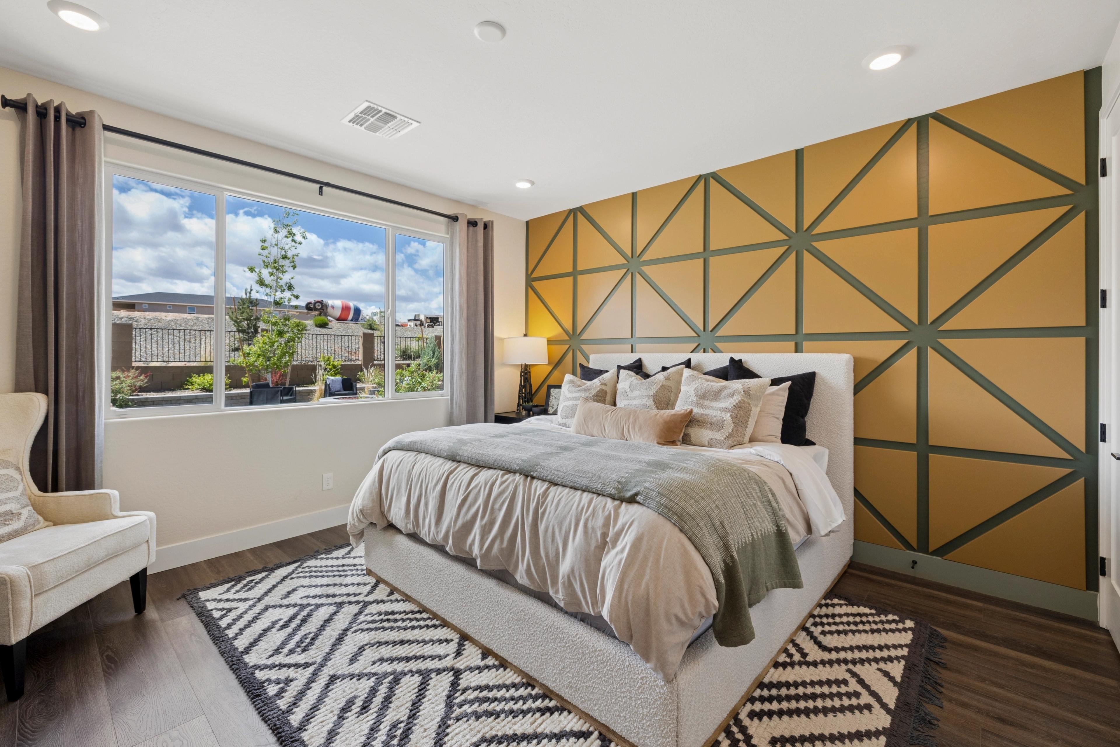 Spacious primary bedroom at South Ranch Western Collection in Prescott AZ with geometric yellow accent wall, king bed and mountain view window