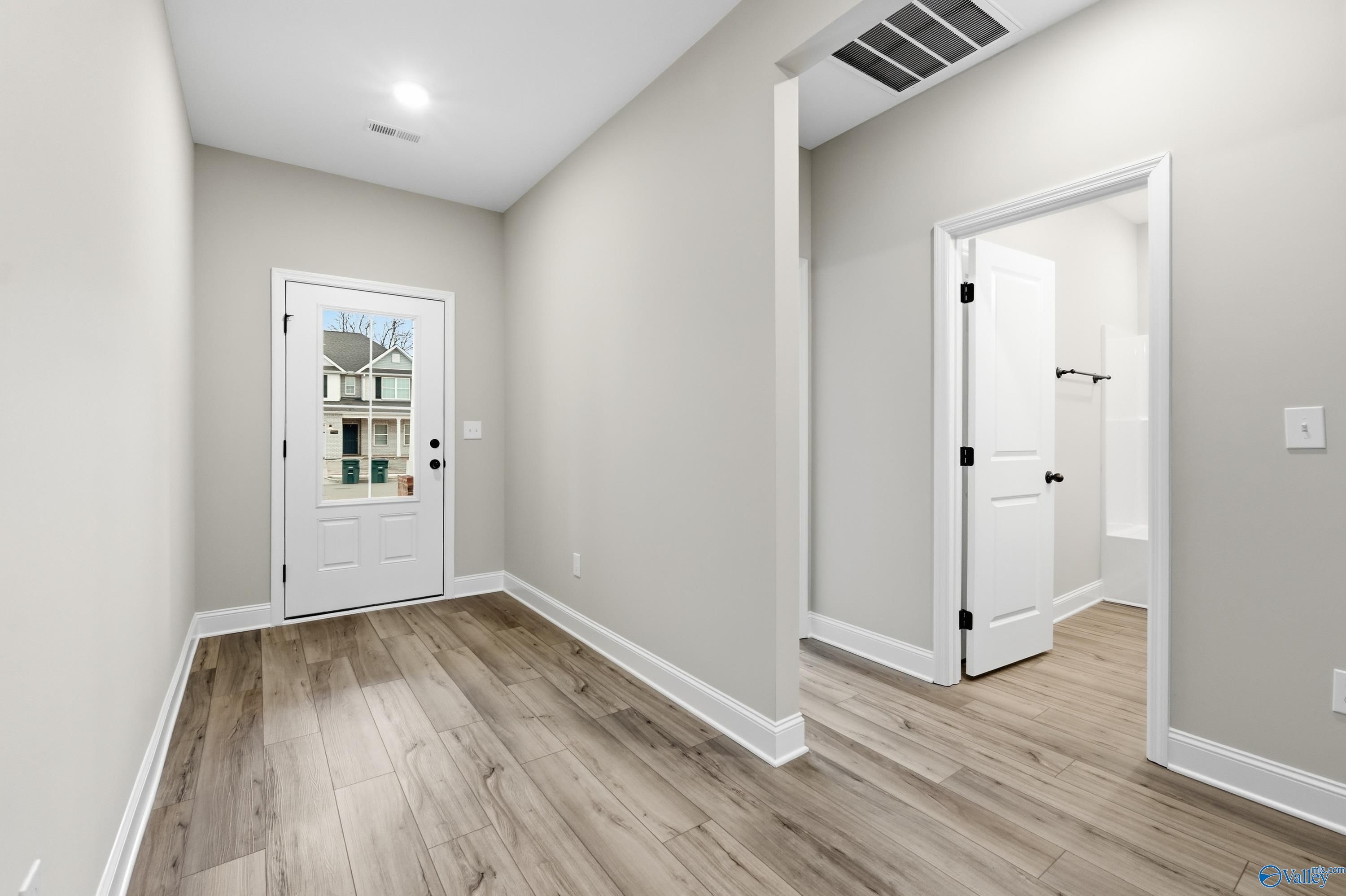 Bright hallway with luxury vinyl plank floors, white doors, and open guest bath vanity in 4-bed Davidson Homes Daphne C, Harvest AL