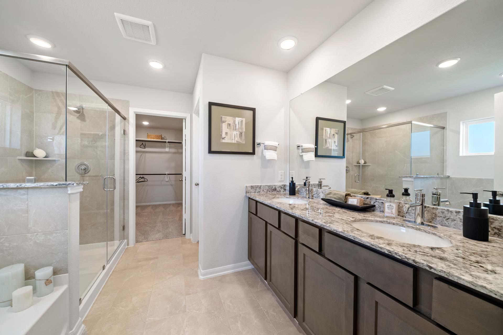 Luxury master bathroom at Windmill Estates in Magnolia TX with double vanity, glass shower, and walk-in closet