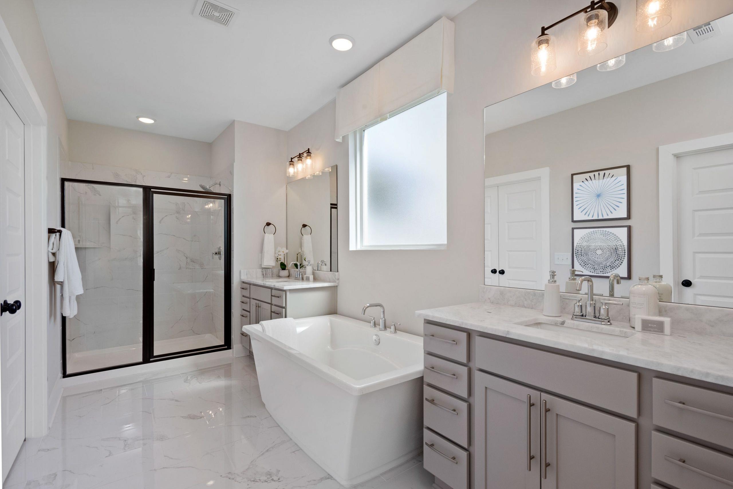Spacious primary bathroom at Rivers Edge in Murfreesboro TN featuring freestanding tub, walk-in glass shower, and double gray vanity