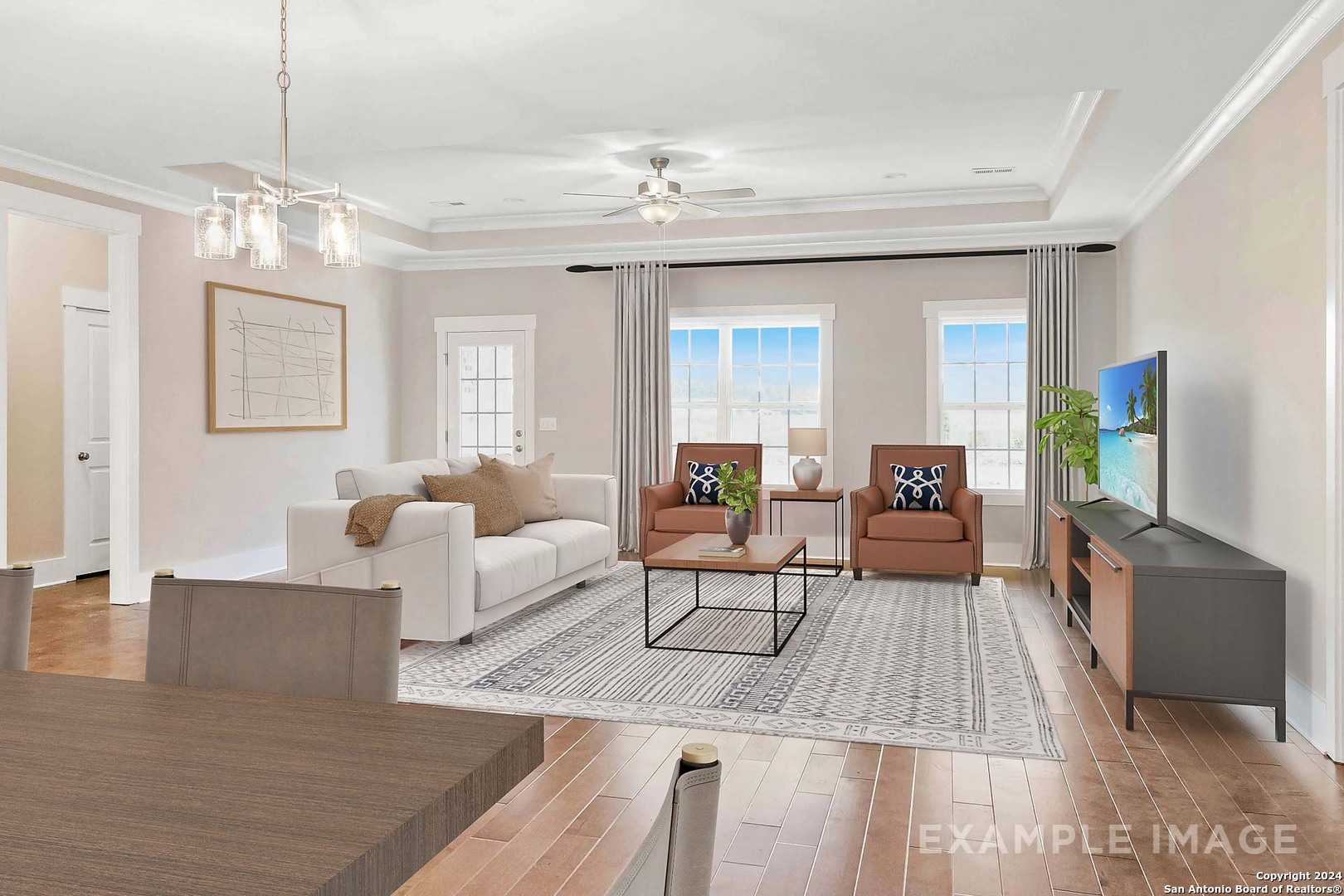Spacious living room with white sofa, armchairs, TV, ceiling fan, and large windows in Davidson Homes The Lanier H, Ladera, San Antonio