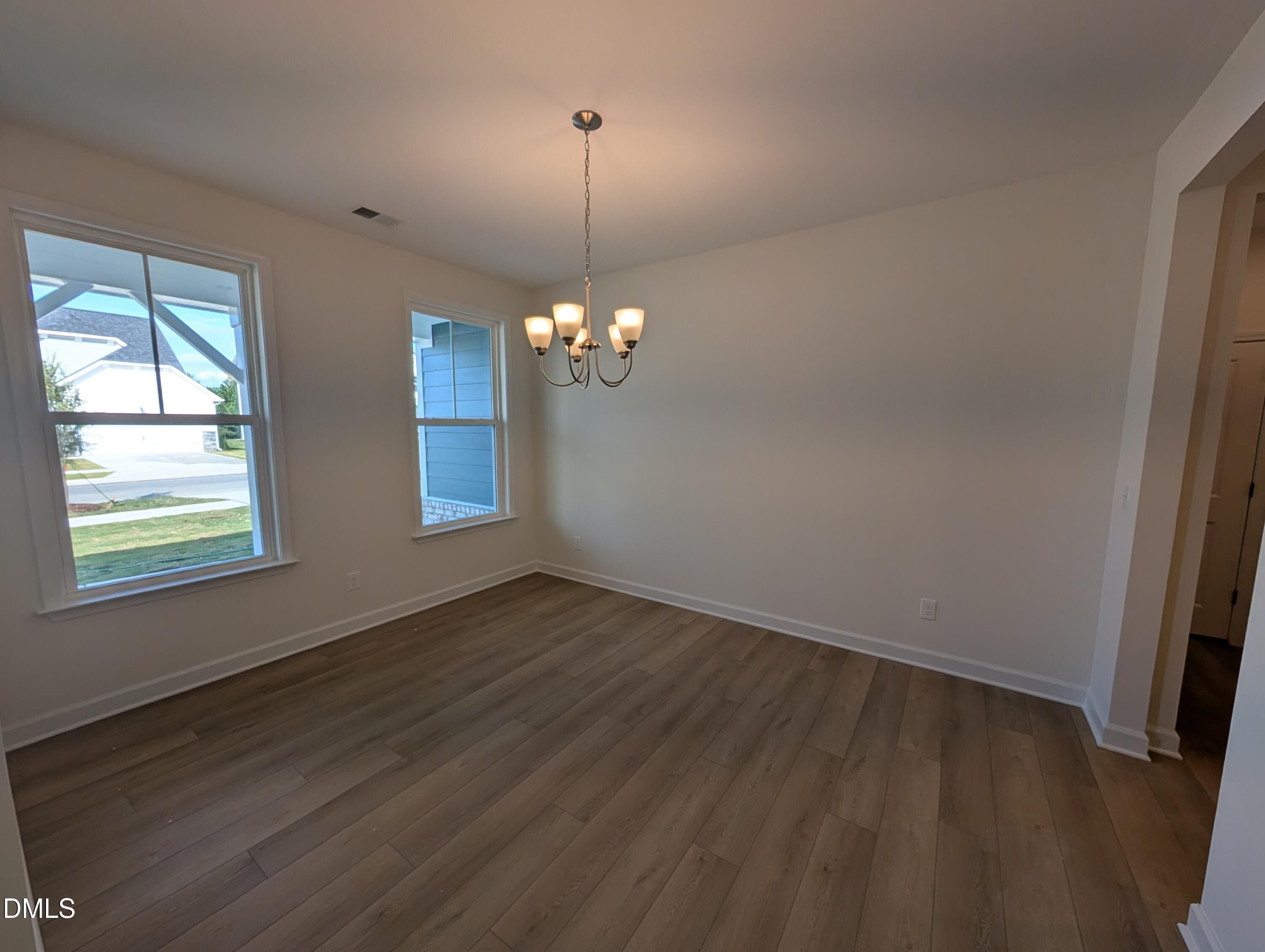 Bright dining room with chandelier, luxury vinyl plank flooring, and double windows in Davidson Homes The Magnolia A, Wendell NC