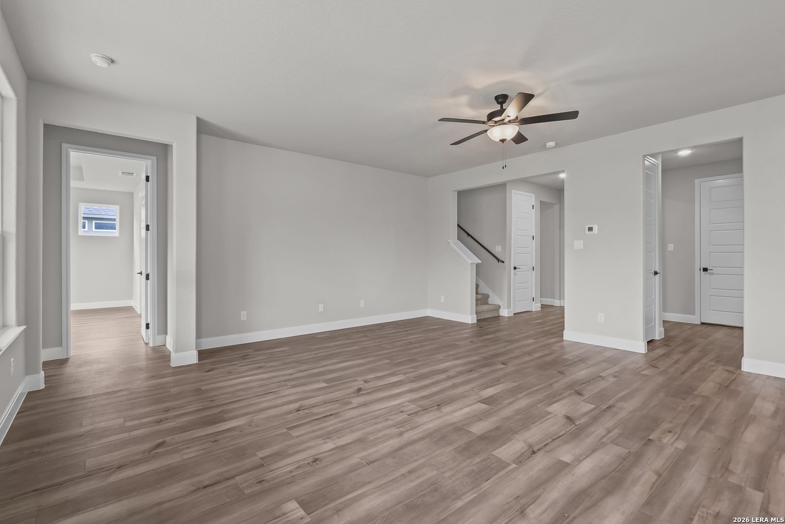 Spacious two-story foyer with hardwood floors, ceiling fan, and open staircase in Davidson Homes The Belmont H, Castroville, Texas