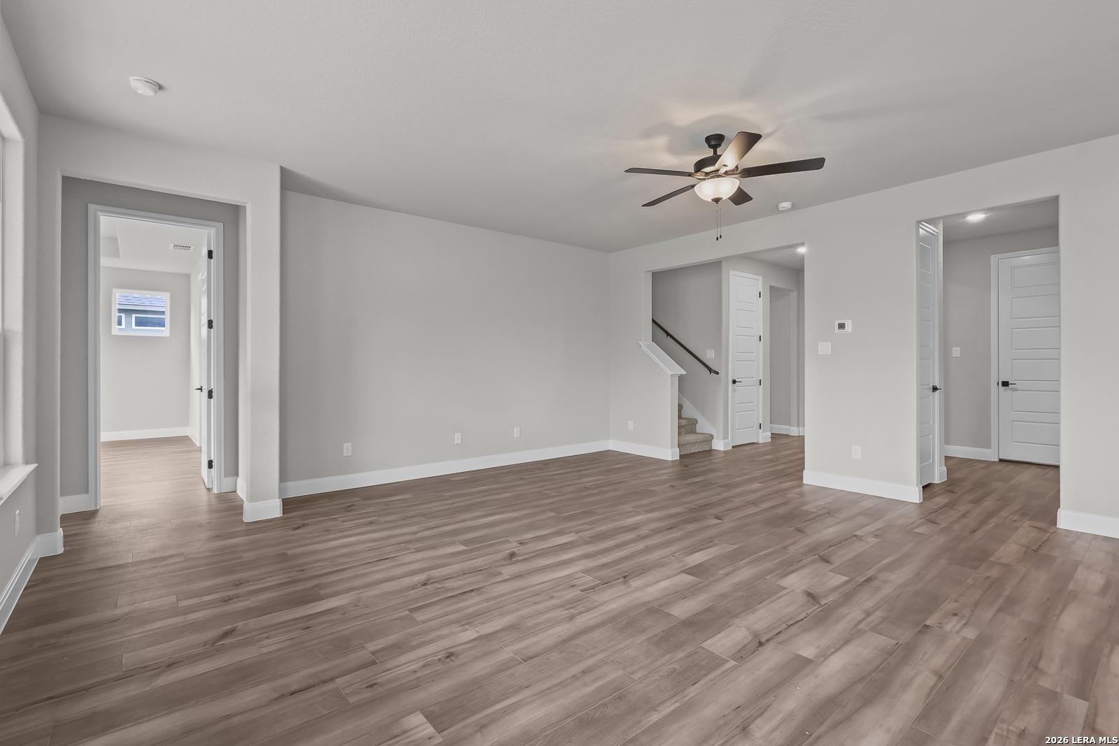 Spacious two-story foyer with hardwood floors, ceiling fan, and open staircase in Davidson Homes The Belmont H, Castroville, Texas