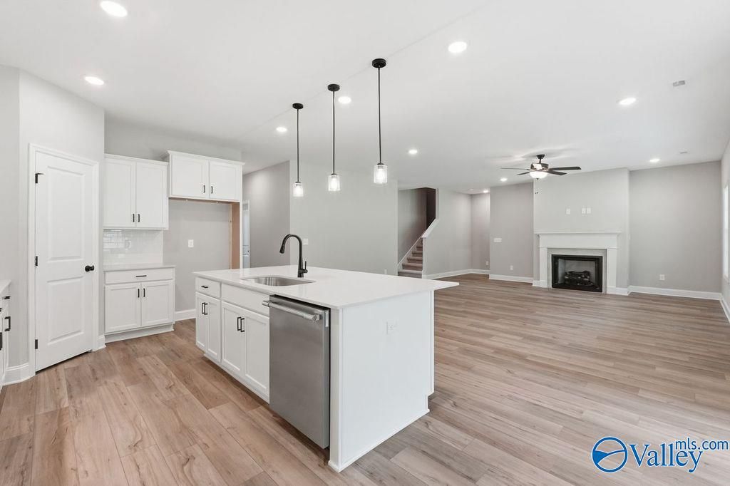 Open-concept kitchen with white island and living room fireplace in The Rockford floor plan at Cain Park, Hartselle, AL.