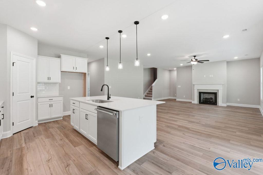 Open-concept kitchen with white island and living room fireplace in The Rockford floor plan at Cain Park, Hartselle, AL.