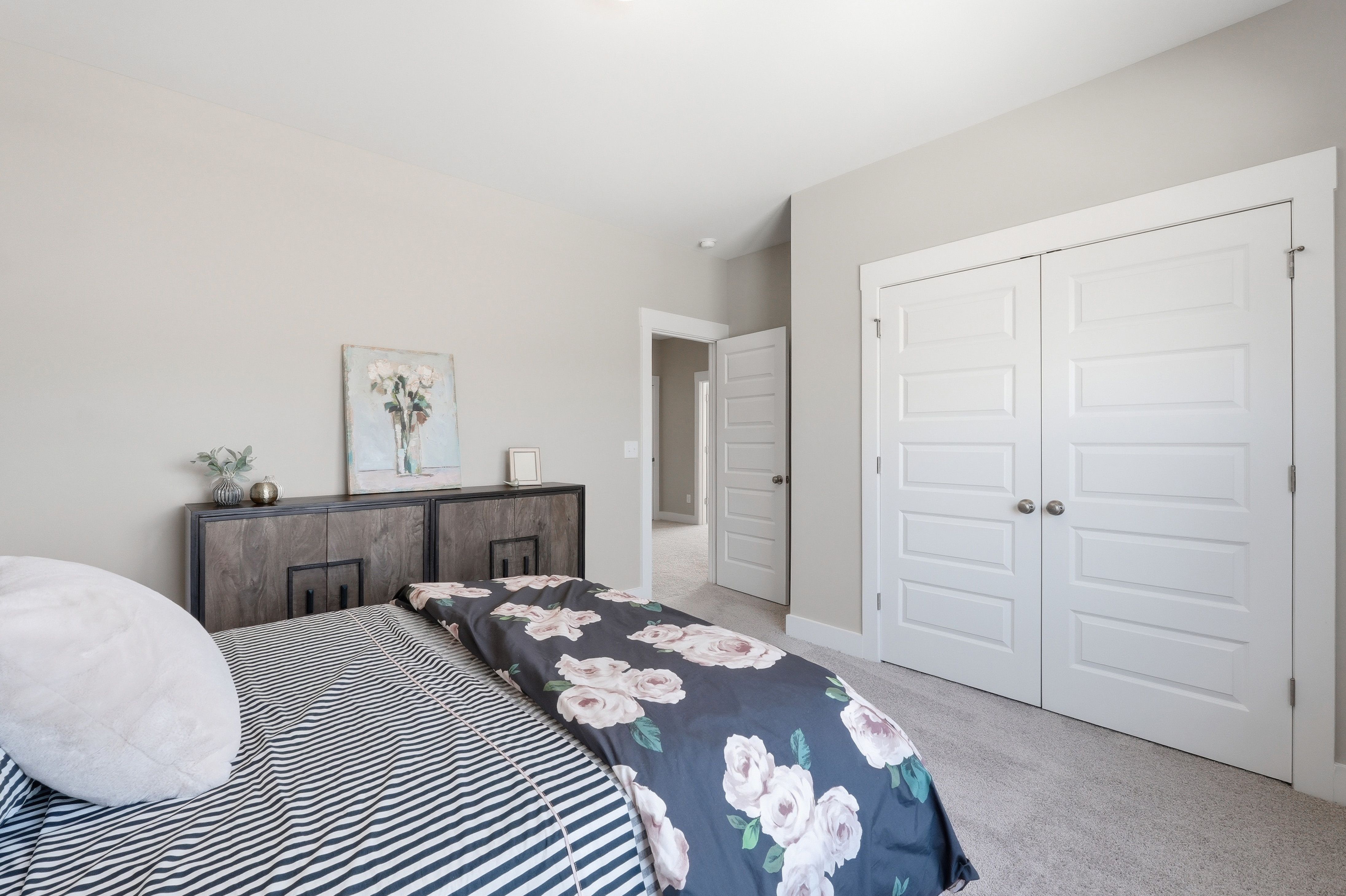 Cozy master bedroom at The Meadows at Hampton Cove in Owens Cross Roads Alabama with floral duvet bed and rustic dresser