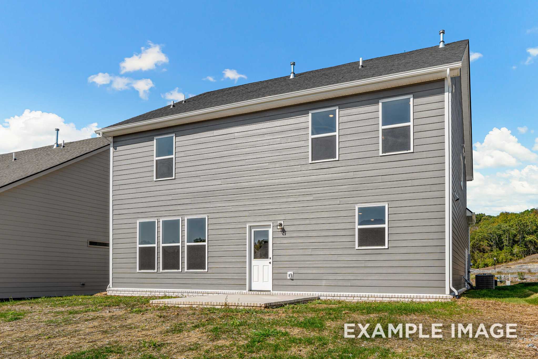 Rear elevation of The Henry C two-story home featuring gray siding, multi-pane windows, and concrete patio in Mt. Juliet