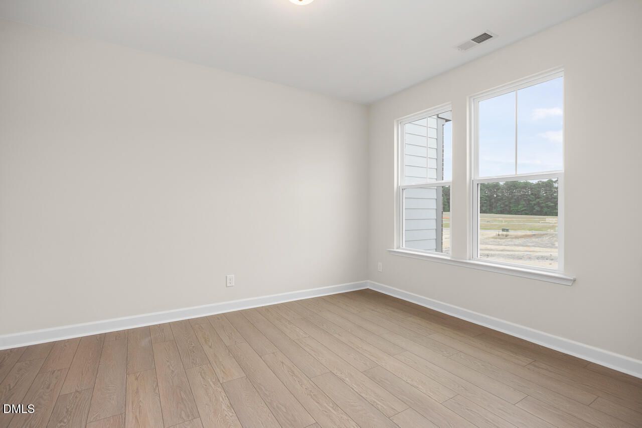 Bright bedroom with light wood flooring and large windows in The Mitchell Interior plan at Forestville Yard, Knightdale, NC.