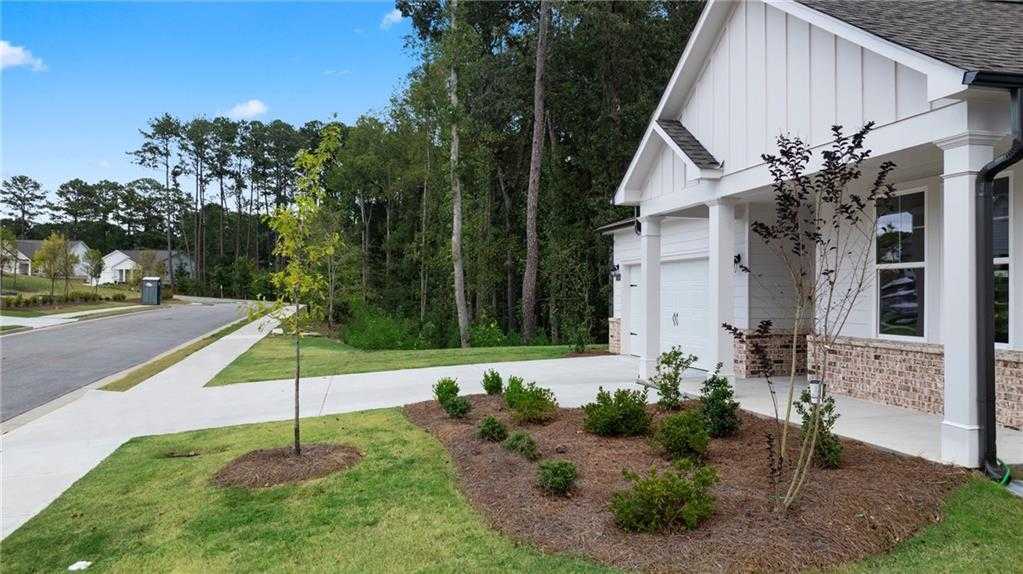 Modern 4-bedroom single-story home exterior with 2-car garage, covered porch, and landscaped yard in Kelly Preserve, Loganville, Georgia by Davidson Homes The Daphne B