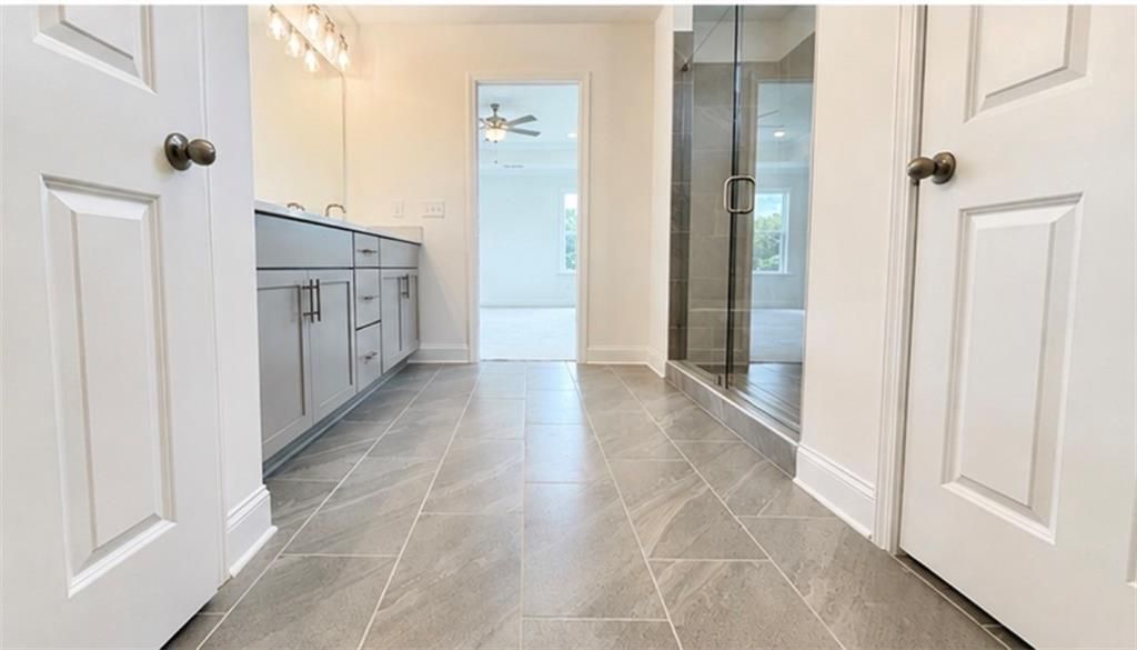 Modern bathroom with gray vanity and glass walk-in shower in The Hickory C floor plan at Wehunt Meadows, Hoschton, Georgia.