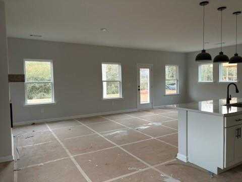 Spacious open living-kitchen area with gray walls, large windows, white island, and pendant lights in Davidson Homes The Rabun C, Winder, GA