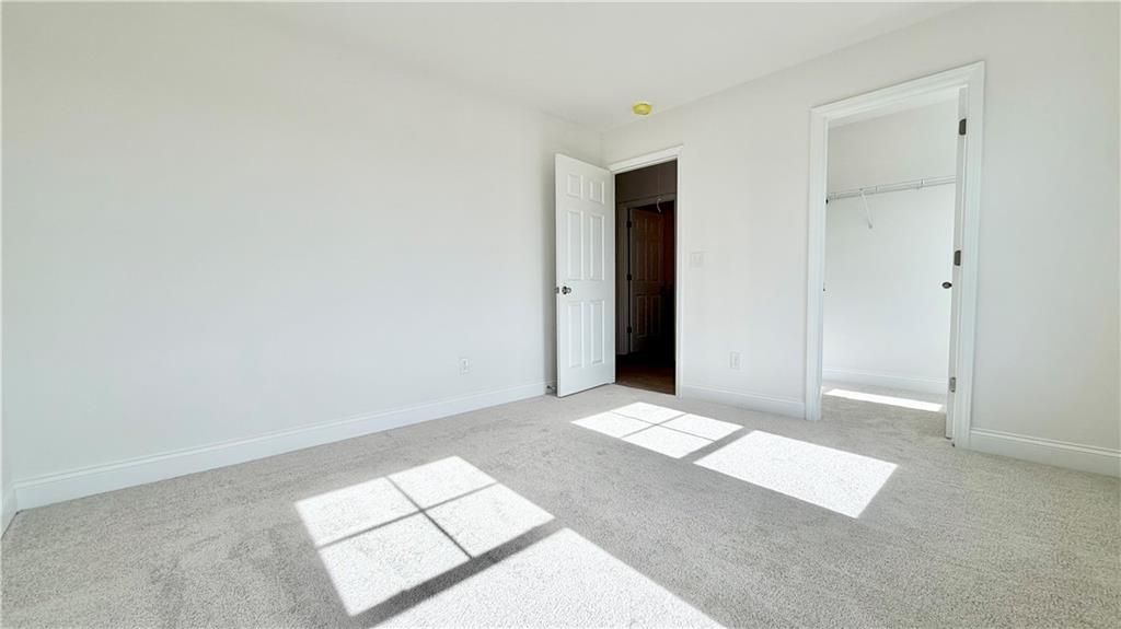 Bright bedroom with neutral carpet and walk-in closet in The Hickory C floor plan at Wehunt Meadows, Hoschton, Georgia.