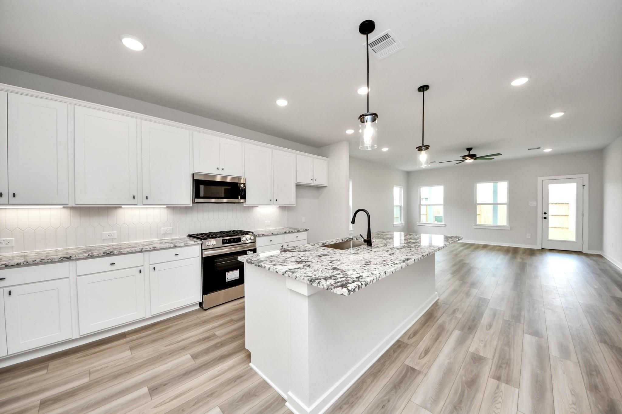 Modern open-concept kitchen with granite island in The Sorrento E floor plan by Davidson Homes in Sundance Cove, Texas.