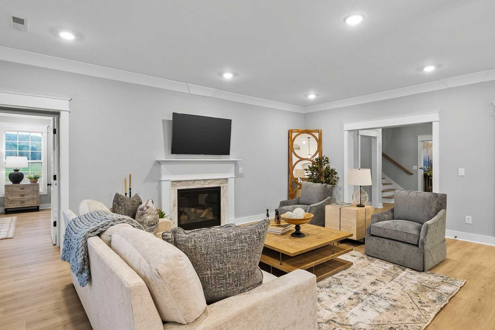 Cozy living room in The Oxford home design with gas fireplace, wall-mounted TV, plush sectional sofa, and neutral gray tones