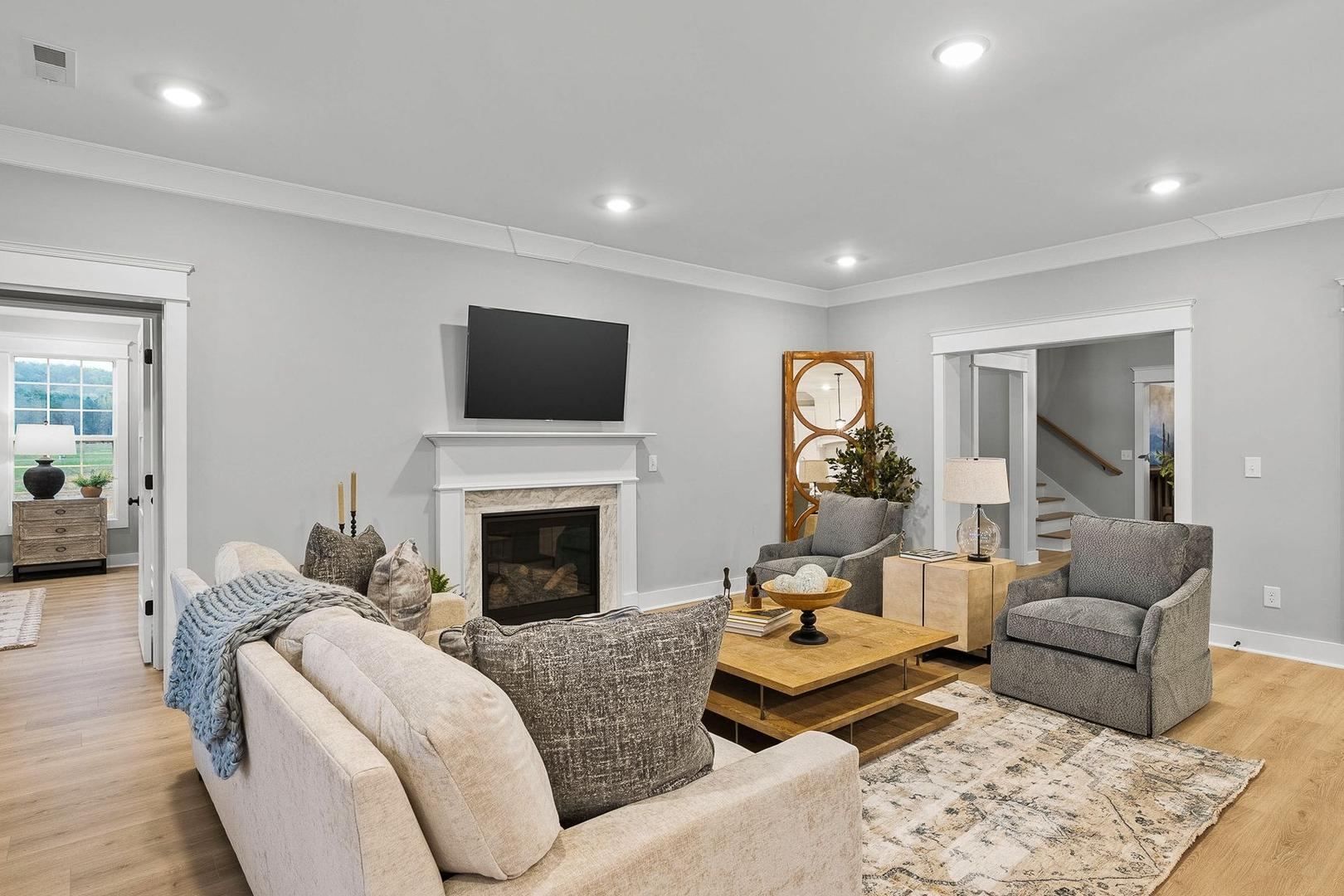 Cozy living room in The Oxford home design with gas fireplace, wall-mounted TV, plush sectional sofa, and neutral gray tones