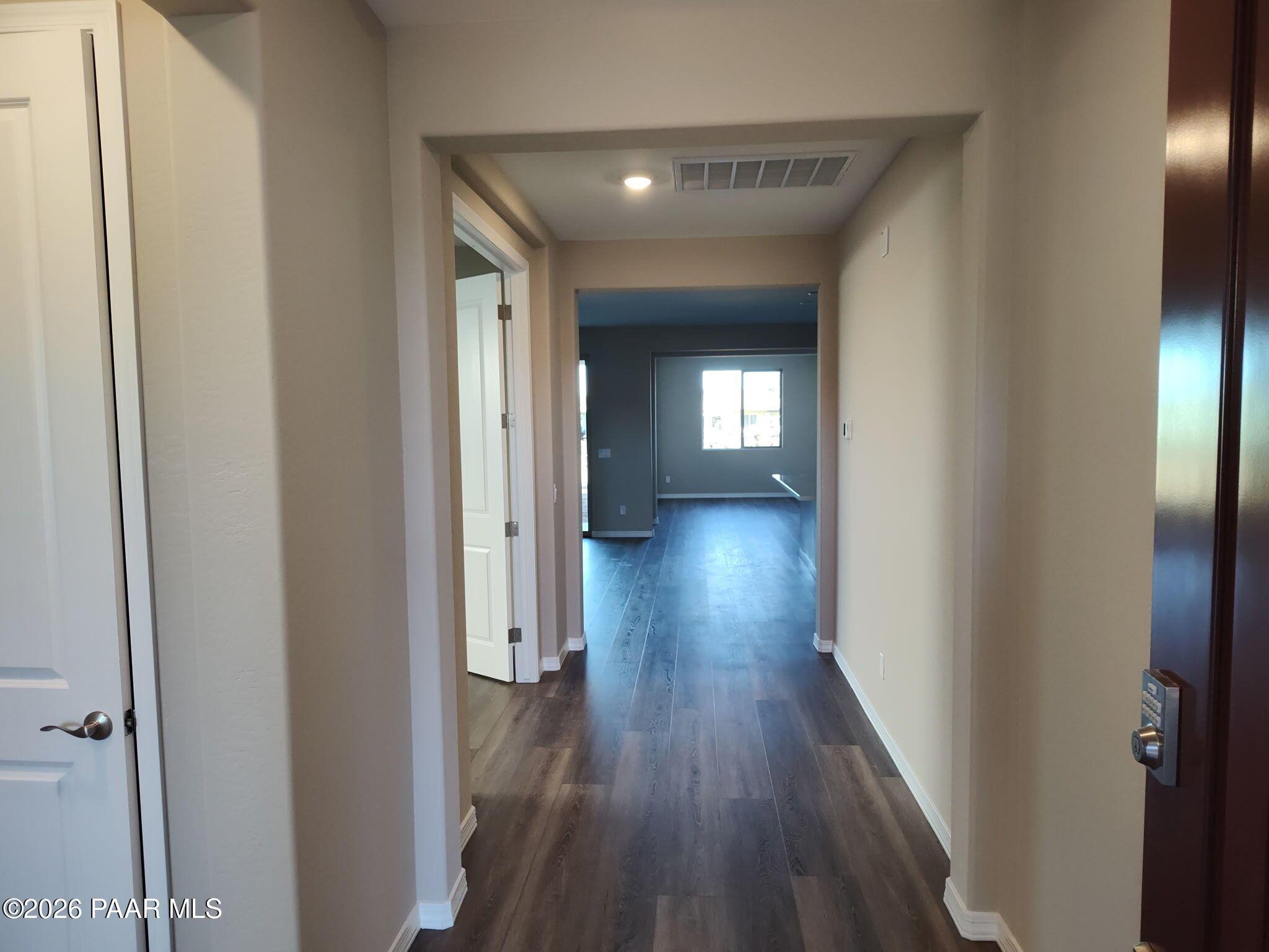 Bright hallway with wood-look flooring leading to open living area in Inspiration C home, North Ridge at Pronghorn Ranch.