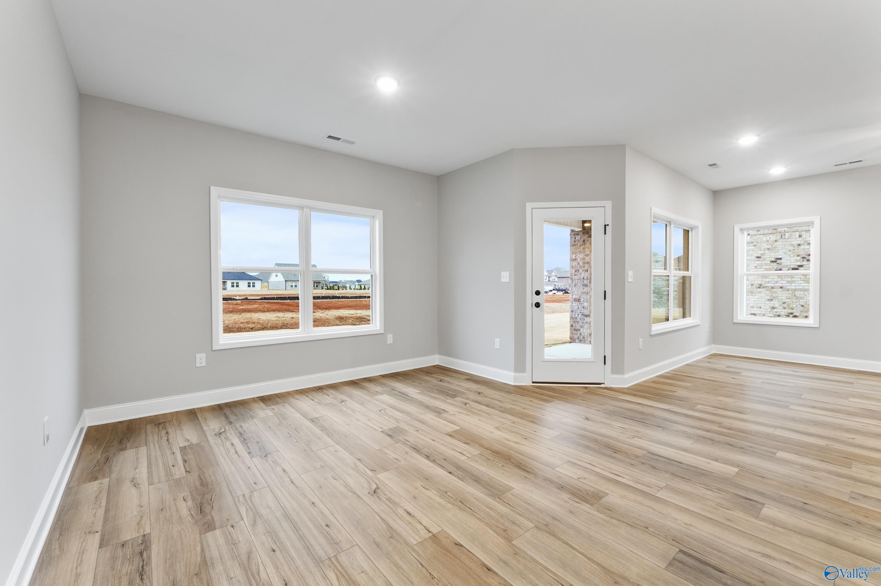 Bright open-concept room with large windows, glass patio door, and hardwood floors in 3-bed Davidson Homes Asheville C, Meridianville AL