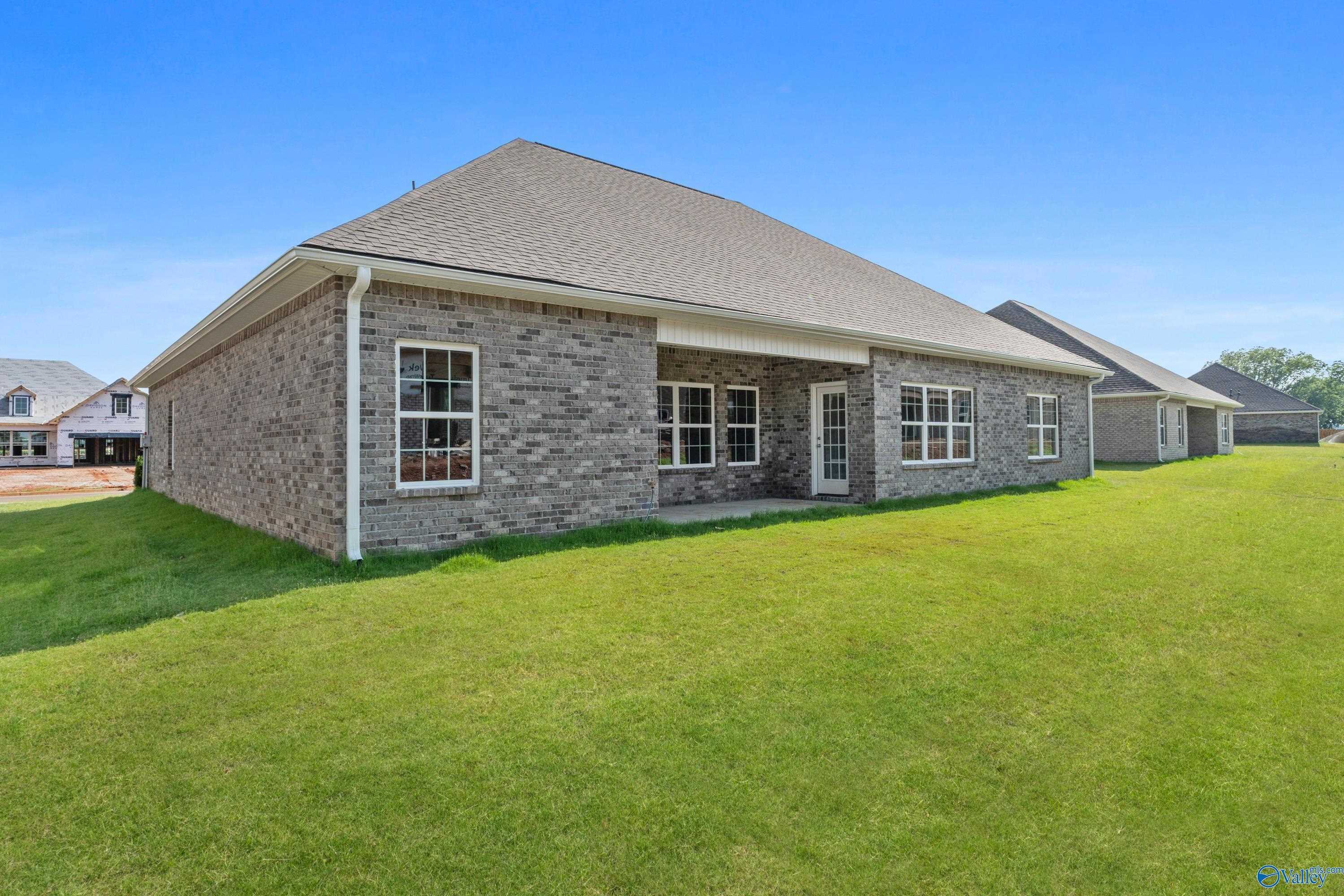 Brick one-story home with 3-car garage and side windows on lush green lawn in Kendall Farms, Toney, Alabama by Davidson Homes The Finleigh