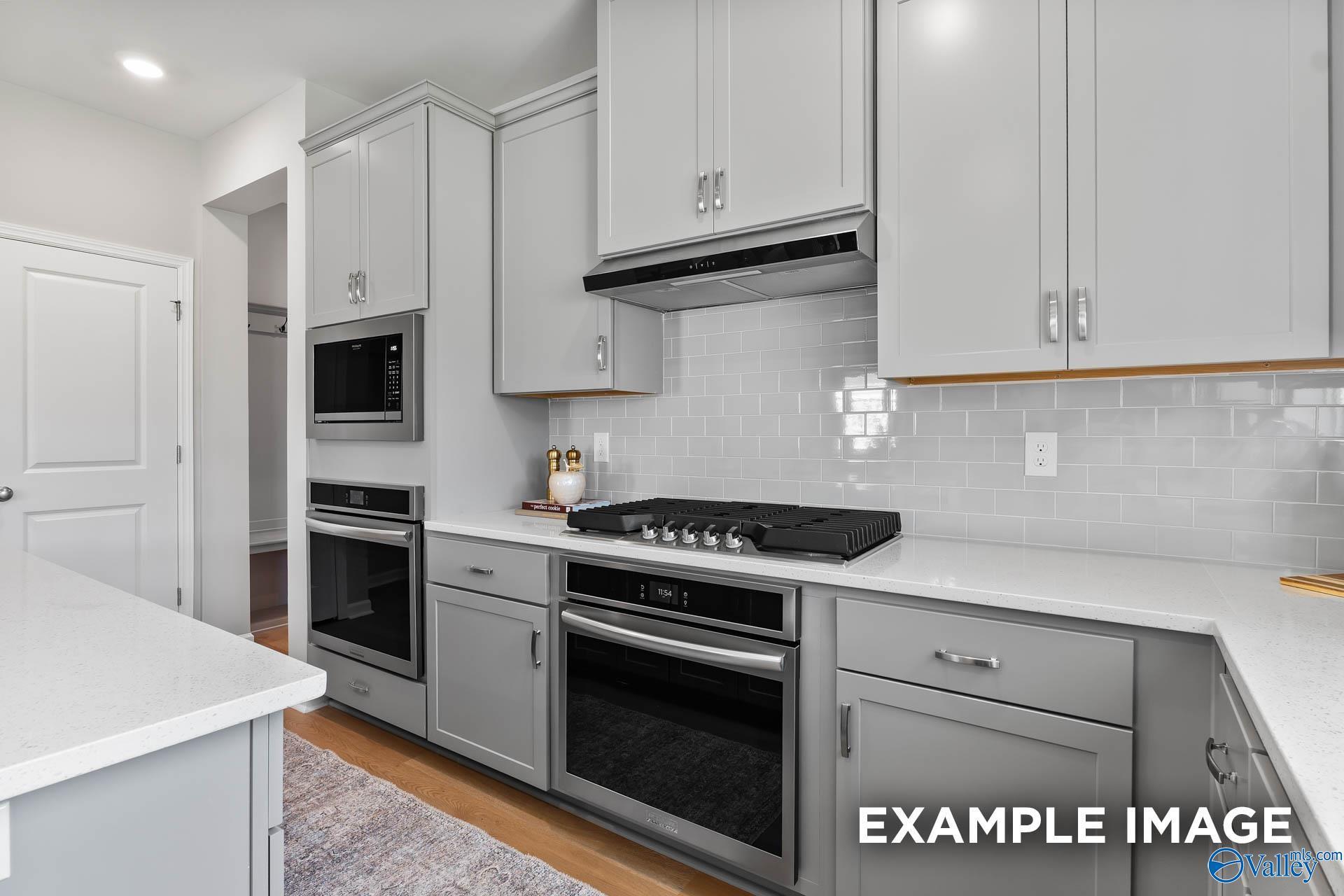 Modern kitchen featuring white shaker cabinets, stainless steel appliances, quartz counters, and subway tile in Davidson Homes The Charm, Huntsville AL