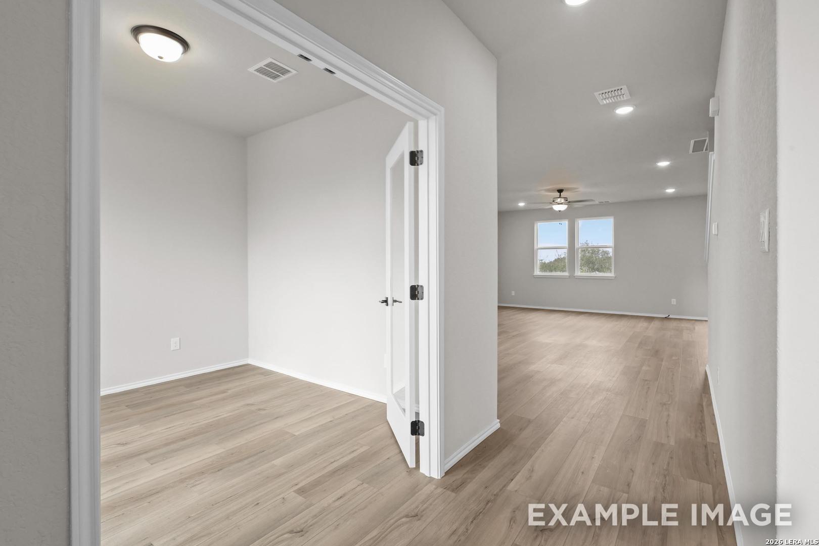 Bright empty room with wood-look flooring and ceiling fan in Davidson Homes The Murray H plan, Converse, Texas