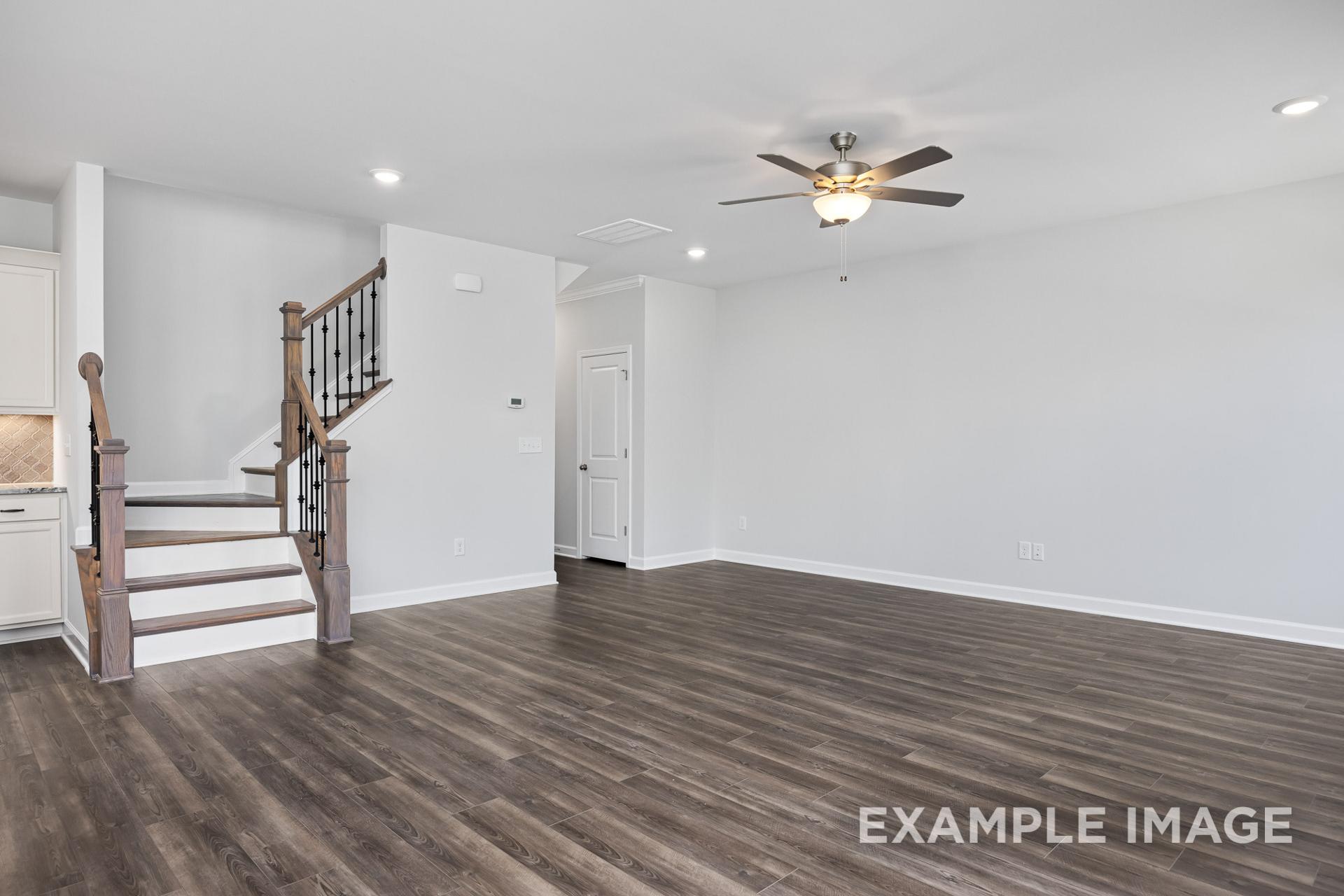 Spacious two-story foyer in The Grace C home design featuring wooden staircase, open living area, hardwood floors, and ceiling fans