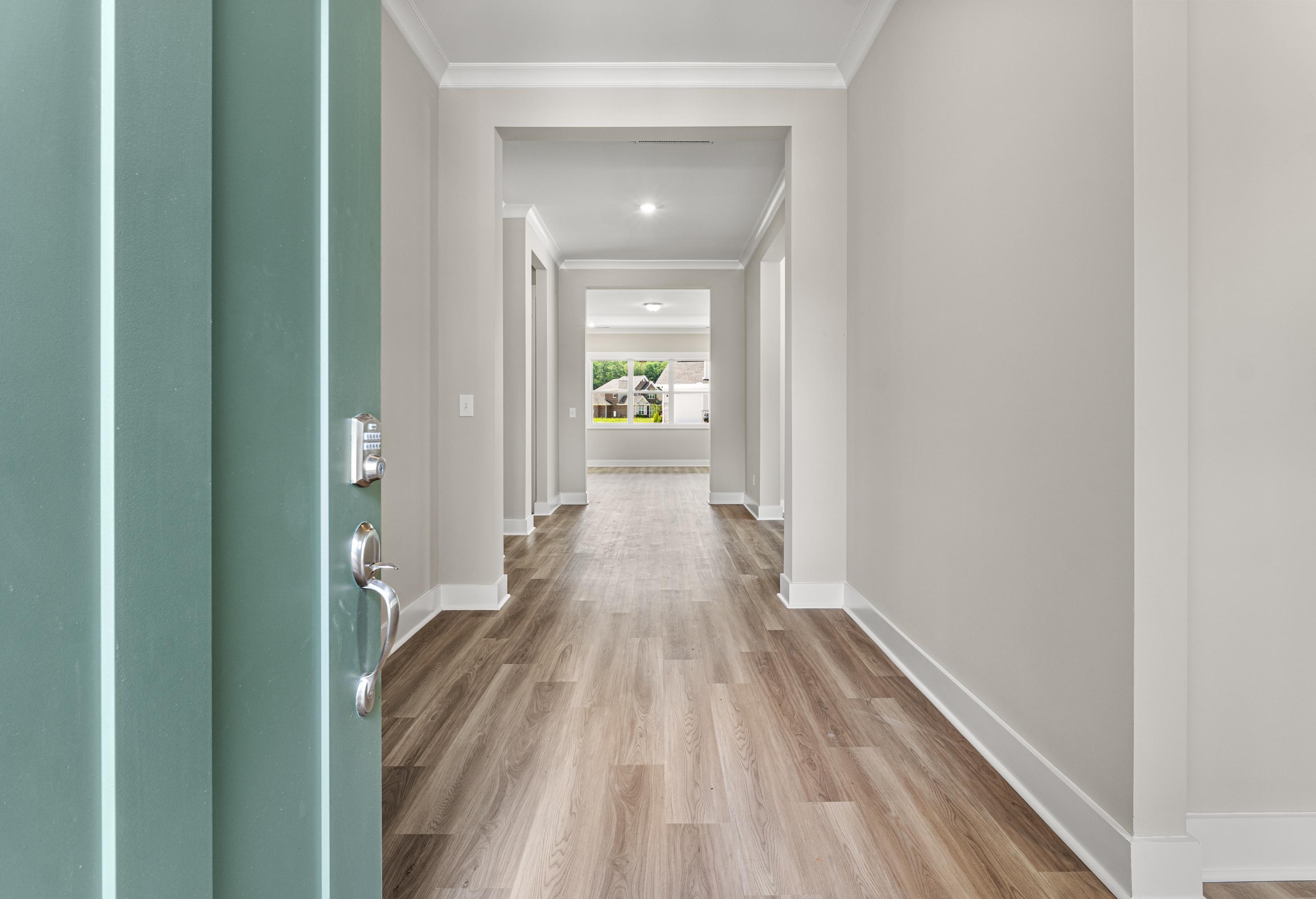 Spacious entry hallway in The Oxford A home with open teal door, light oak floors, neutral walls, and natural light