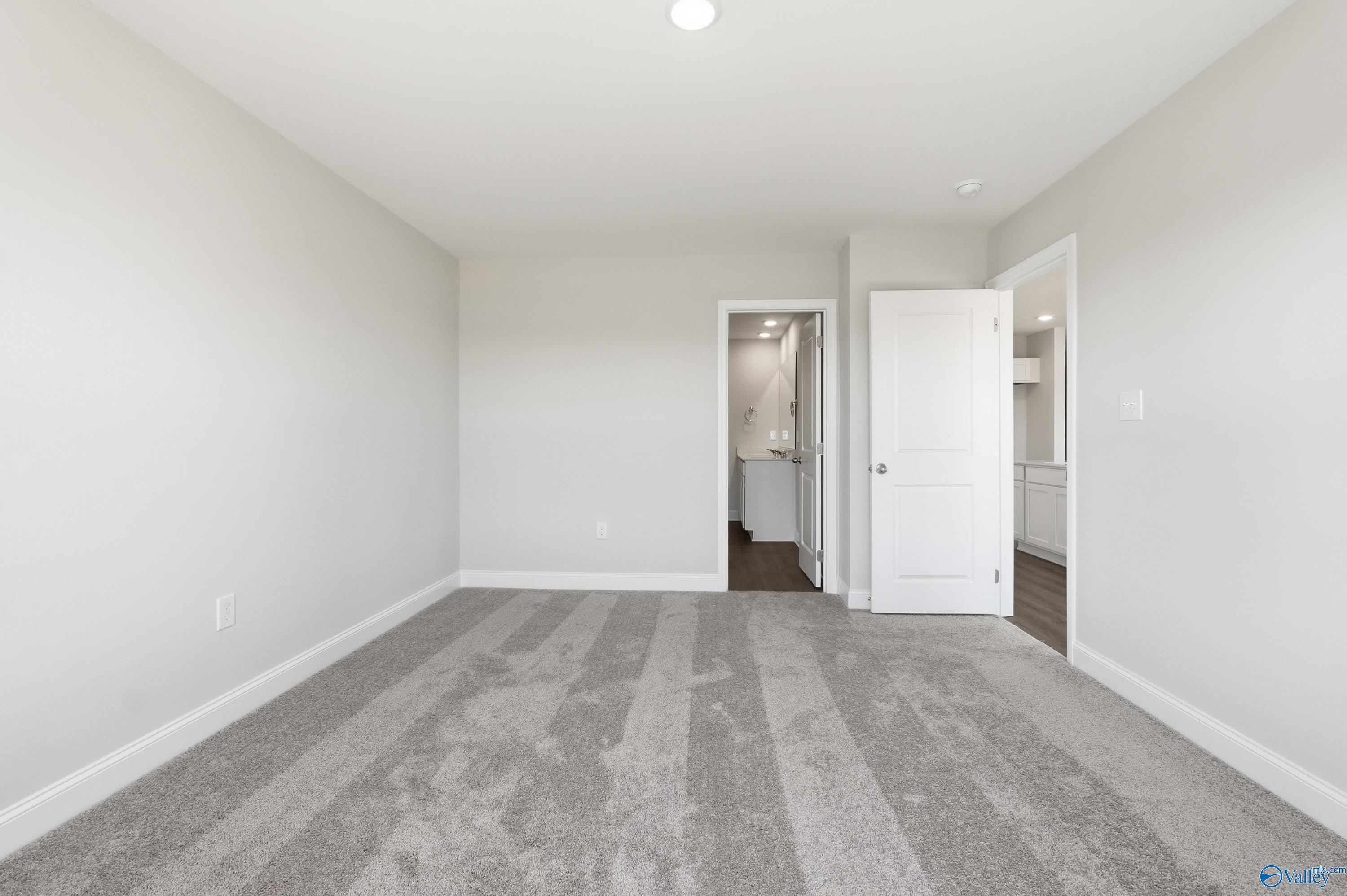Spacious secondary bedroom with gray carpet, white walls, and adjacent bathroom in Davidson Homes The Franklin, New Market, Alabama