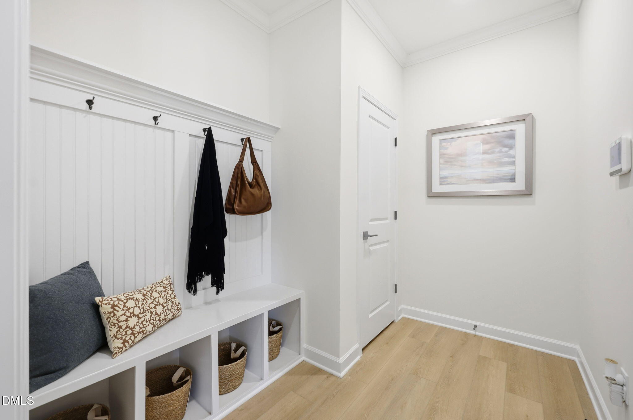 White mudroom with built-in bench, coat hooks, and storage cubbies in The Aspen B home at Wendell Ridge, North Carolina.