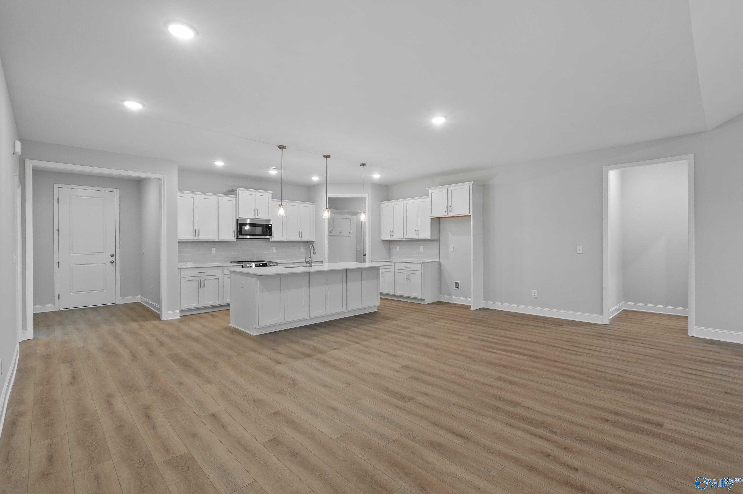 Modern white kitchen island with stainless appliances and open layout in The Lanier 4-bedroom home, Harvest, Alabama