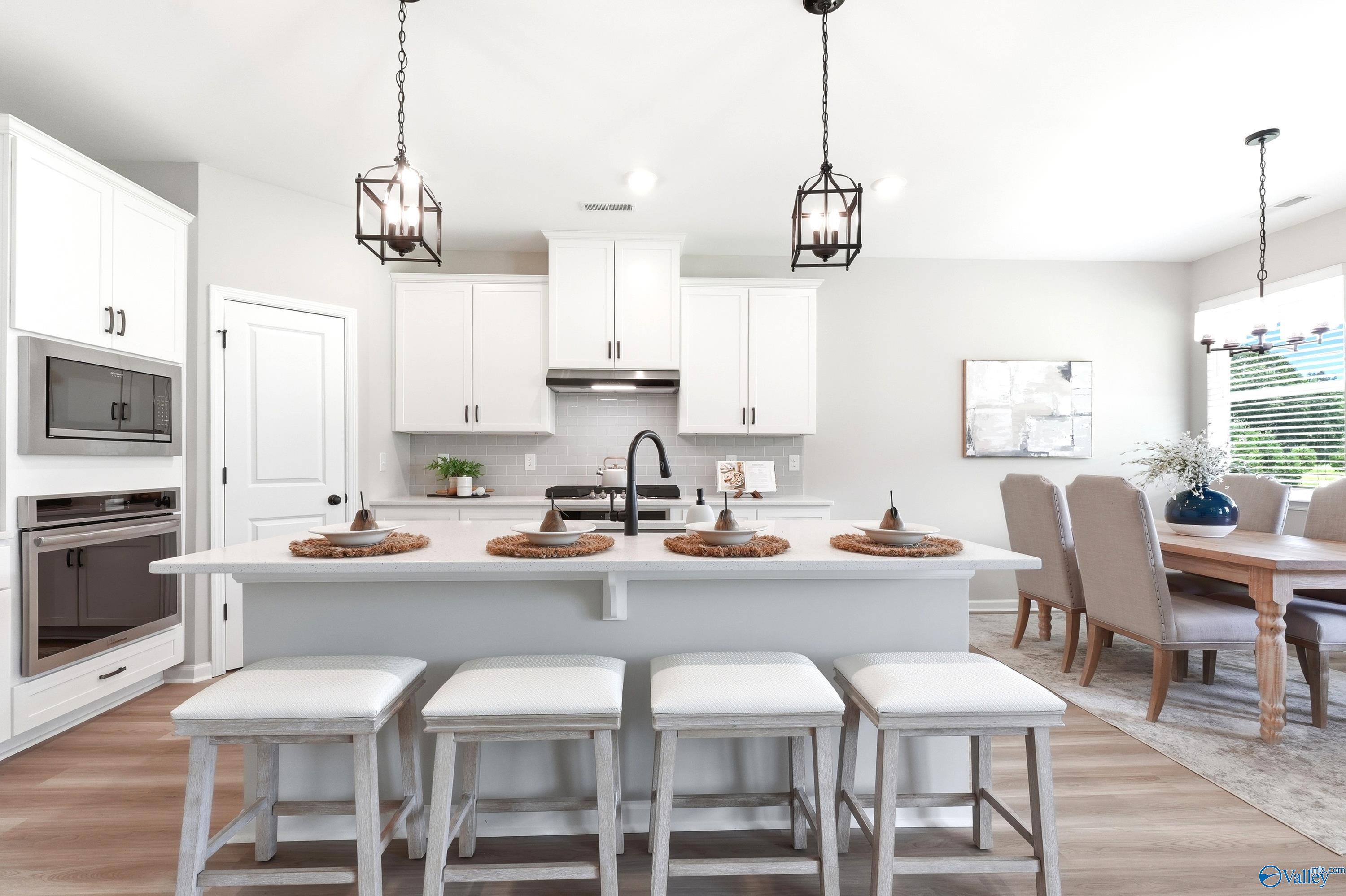 Modern kitchen with white cabinets, large island, and dining area in The Dorado floor plan at Riverton Preserve, Huntsville.