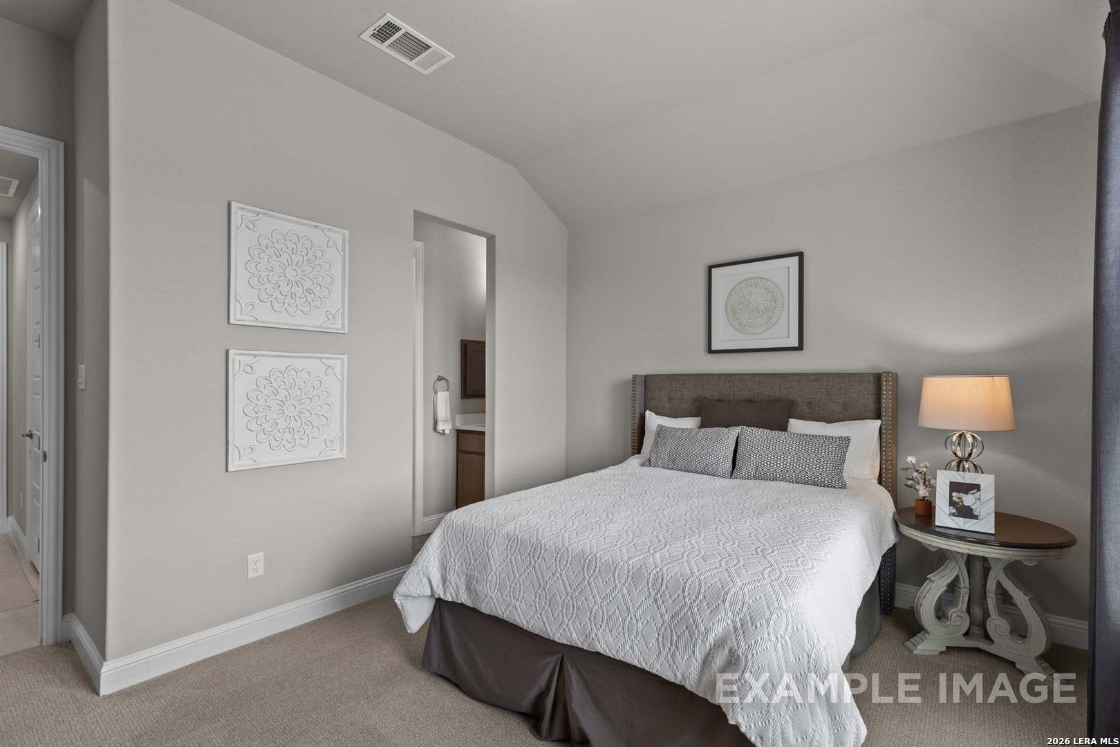 Cozy guest bedroom with neutral decor and en-suite bath in The Garner C floor plan at The Reserve at Potranco Oaks.