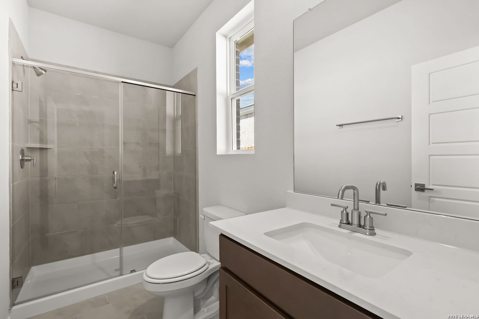 Modern bathroom with glass walk-in shower, white vanity, and natural light in Davidson Homes The Daphne I, Bricewood, San Antonio