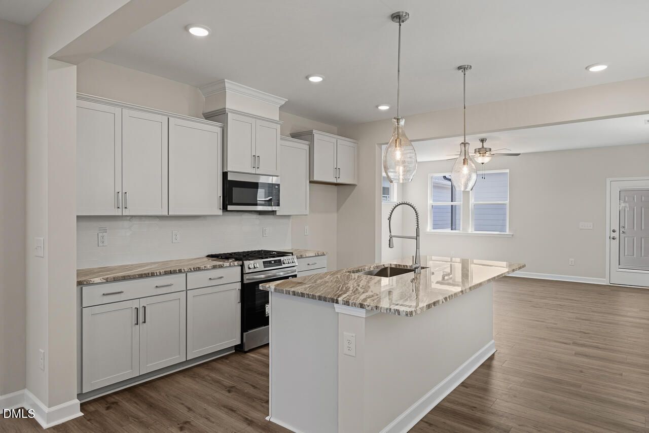 Modern kitchen with granite island and light gray cabinetry in The Alexander C floor plan, Forestville Yard, Knightdale, NC.